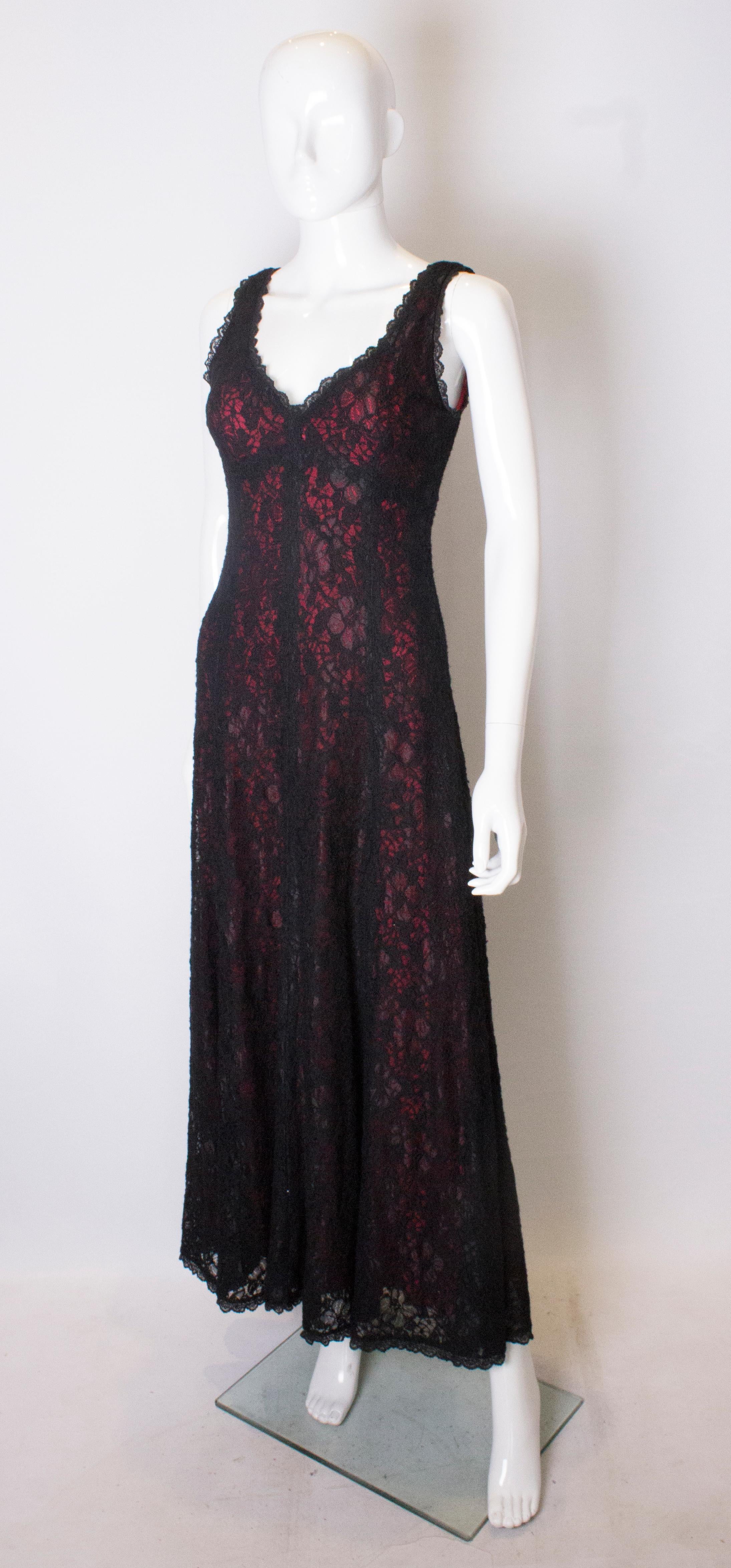 A great statement dress from Caroline Charles. The dress is in black lace with a red lining. It has a v neckline , and backline with central back zip.