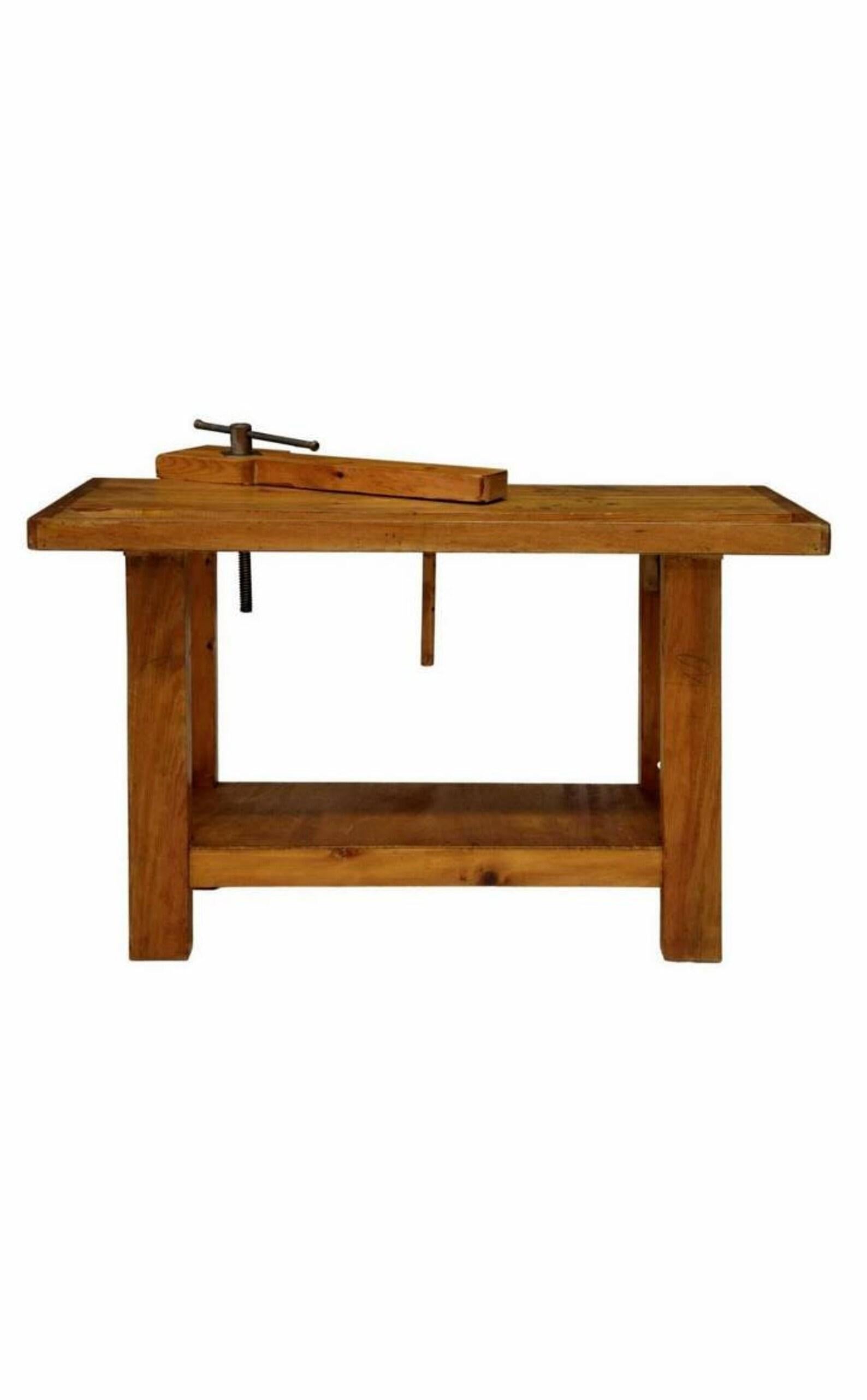 A vintage carpentry woodworking - craftsman's pine workbench.

Dating to the first half of the 20th century, having a thick rectangular solid pine top with desirable overhang and recessed chanel trough, single hand crank vice clamp with heavy iron