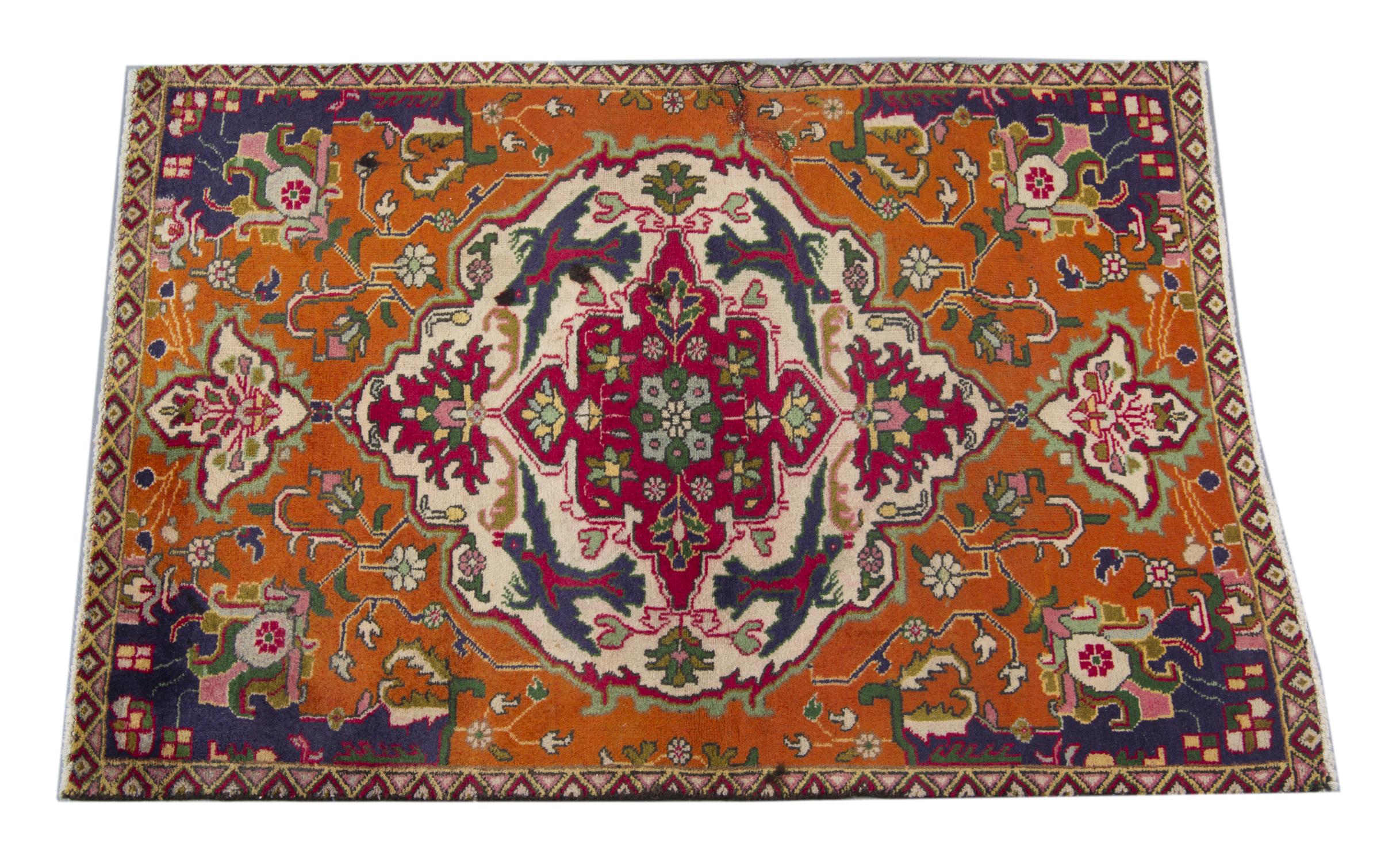 This elegant floral carpet was woven by hand in the 1950s. The central design has been woven on orange background with accents of green, ivory, pink and red that make up the oriental symmetrical design. Delicately woven with intricate details