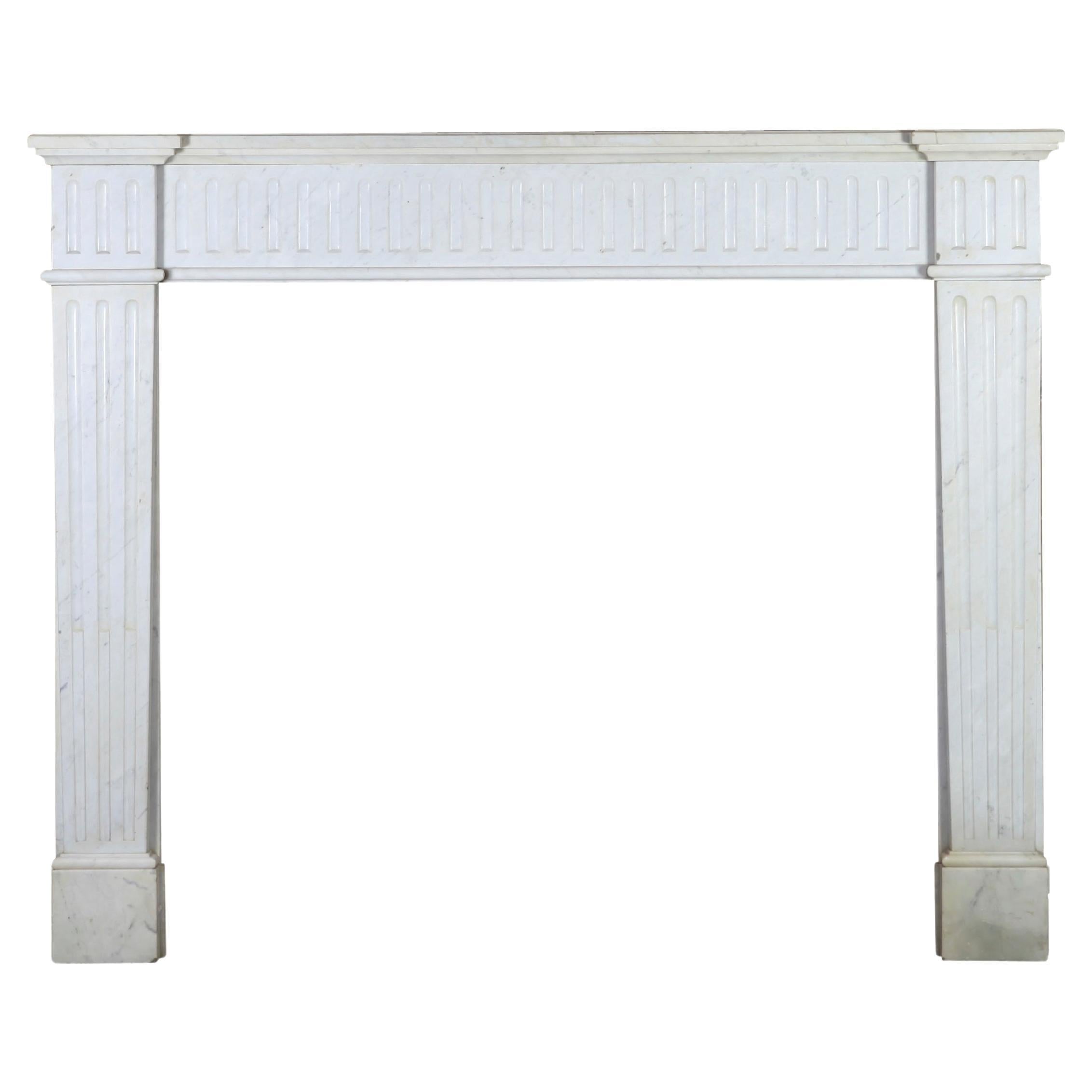 Original simple vintage fireplace surround from a Belgium home in white Carrara marble. It is a Louis XVI style from the 19th century. 
Measures:
135 cm Exterior Width 53,15 Inch
108 cm Exterior Hight 42,52 Inch
102 cm Interior Width 40,15 Inch
88