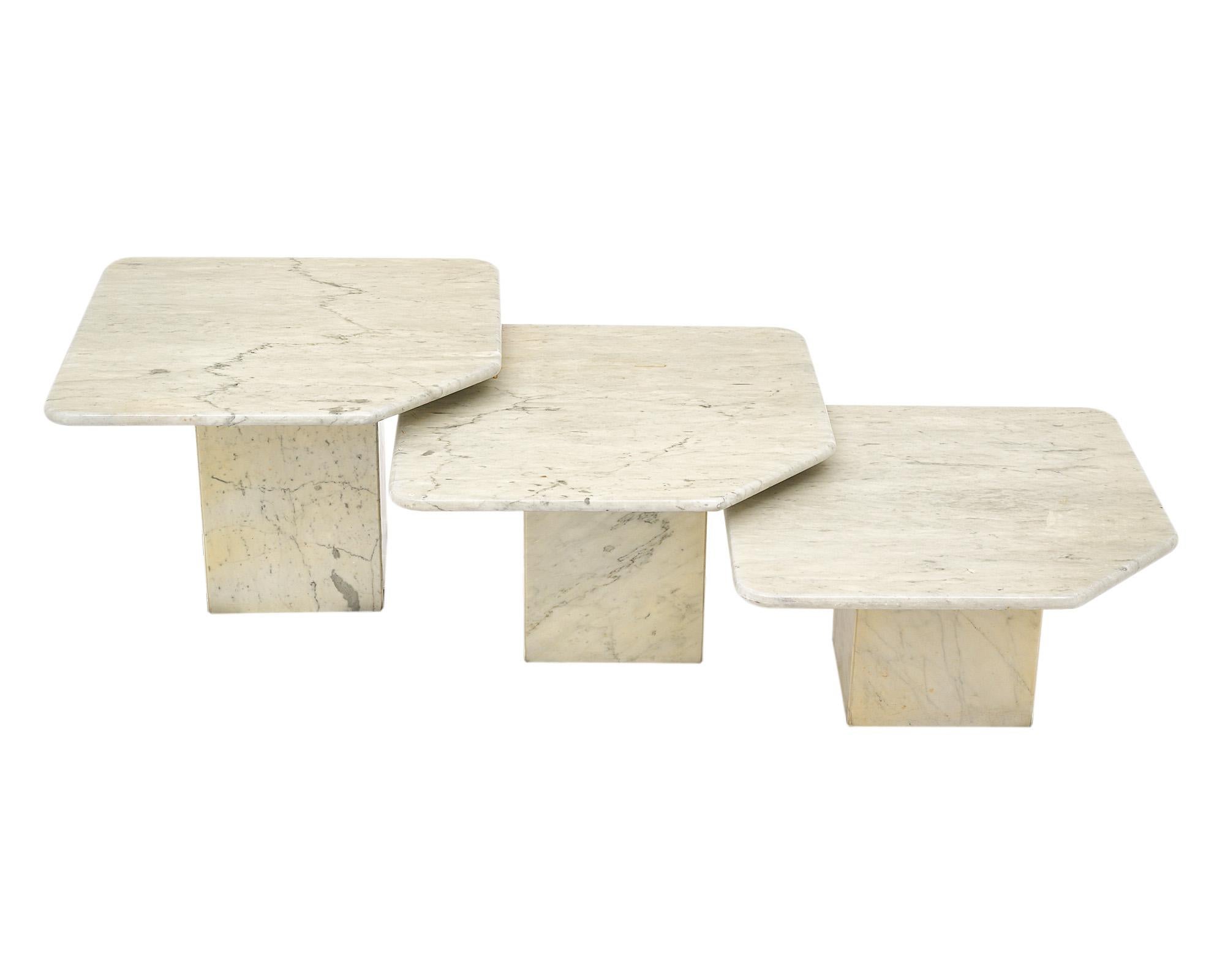 Ensemble de trois tables gigognes en marbre de Carrare. Chaque table repose sur une base carrée en marbre. Les plateaux en marbre sont de forme carrée avec des coins arrondis et chacun d'entre eux présente un coin coupé qui est à la fois graphique