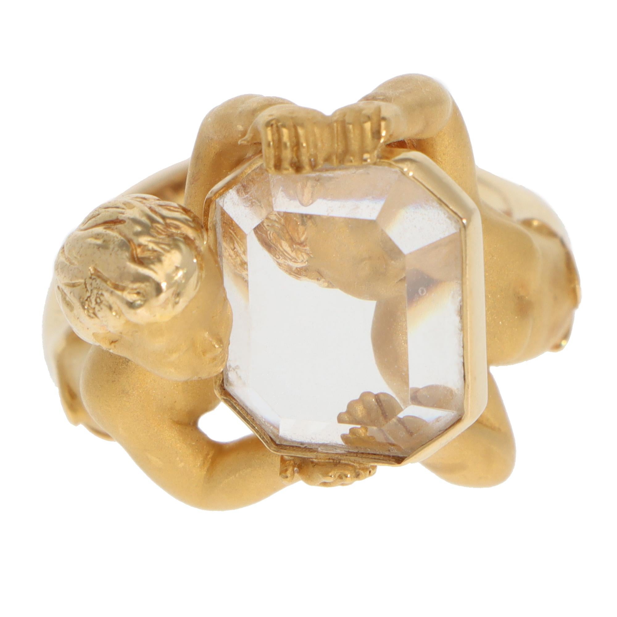 Precioso anillo vintage Carrera y Carrera de cuarzo Narciso engastado en oro amarillo de 18 quilates.

El anillo está compuesto por dos figuras de querubines de oro amarillo cepillado que sostienen una pastilla de cristal de roca incoloro talla