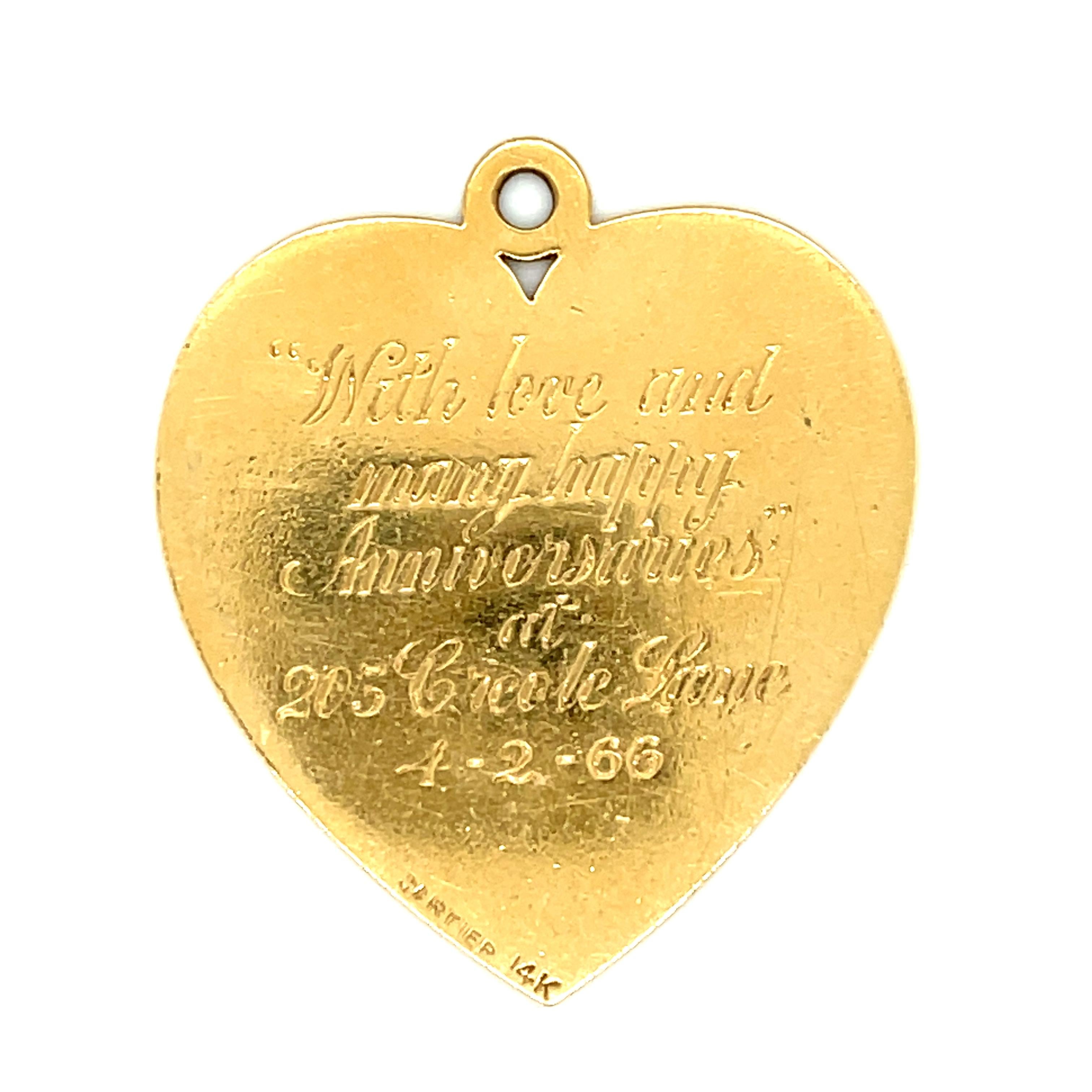 A pretty 14k yellow gold heart charm by Cartier with an engraved home on the front of the heart, from 1966. The charm has a detailed engraved house surrounded by trees on the front. The reverse has the inscription, “With love and many happy