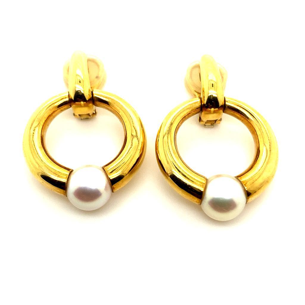 A pair of vintage Cartier 18 karat yellow gold pearl drop earrings

Designed as an open circle set with a cultured pearl of 8mm and suspended from a plain polished half hoop finished with clip fittings.

The mid size of these earrings mean that they