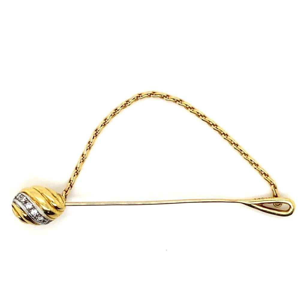 A vintage Cartier 18 karat yellow gold tie pin, circa 1960.

This elegant tie pin by Cartier features an oval ball to its top designed with curved lines of plain polished yellow gold grain set with a single row of round brilliant cut diamonds in