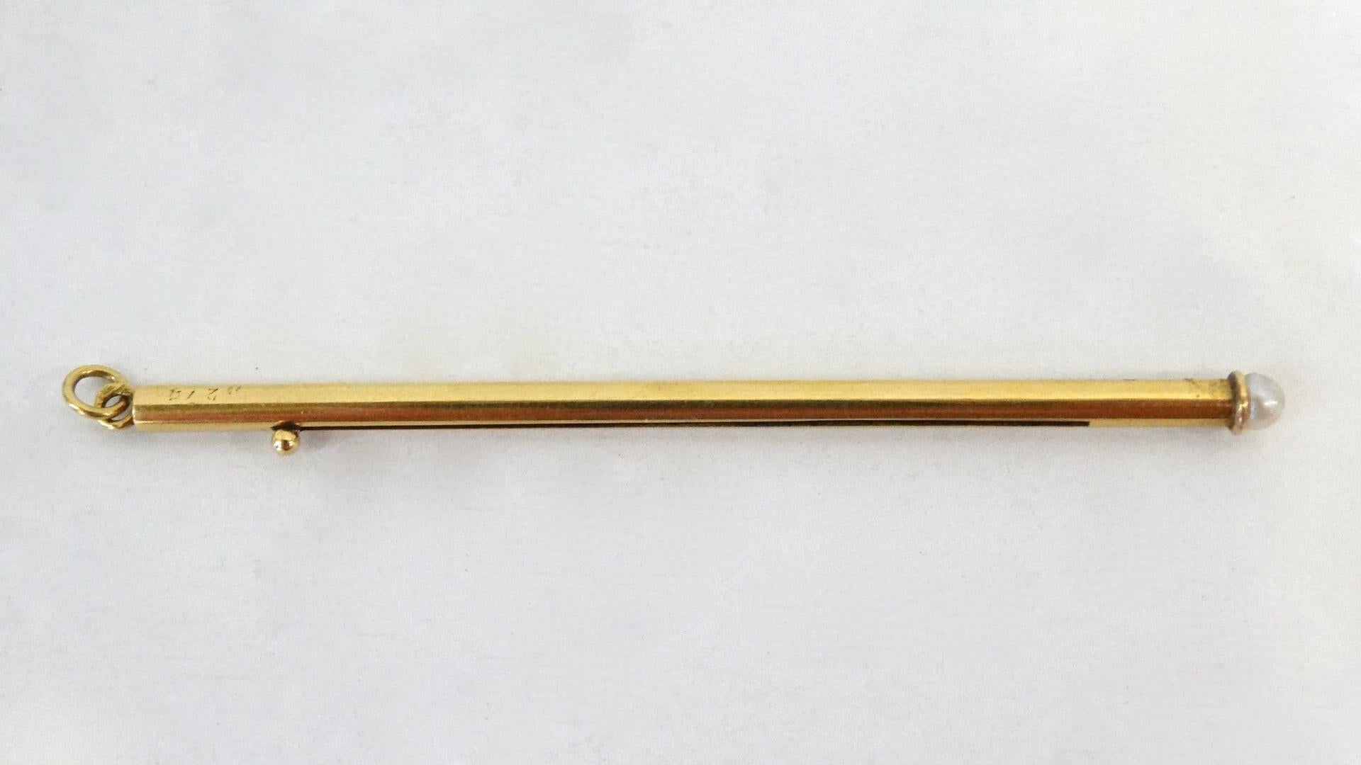  An 18 carat gold Champagne stirrer that can be worn as a pendant,  signed and numbered: Cartier, 279, in velvet case with a natural pearl on middle stem.
weight: 6.90 grams dimensions: 7.5 x 0.5 cm. Made in France. This now-rare device, an 18 carat