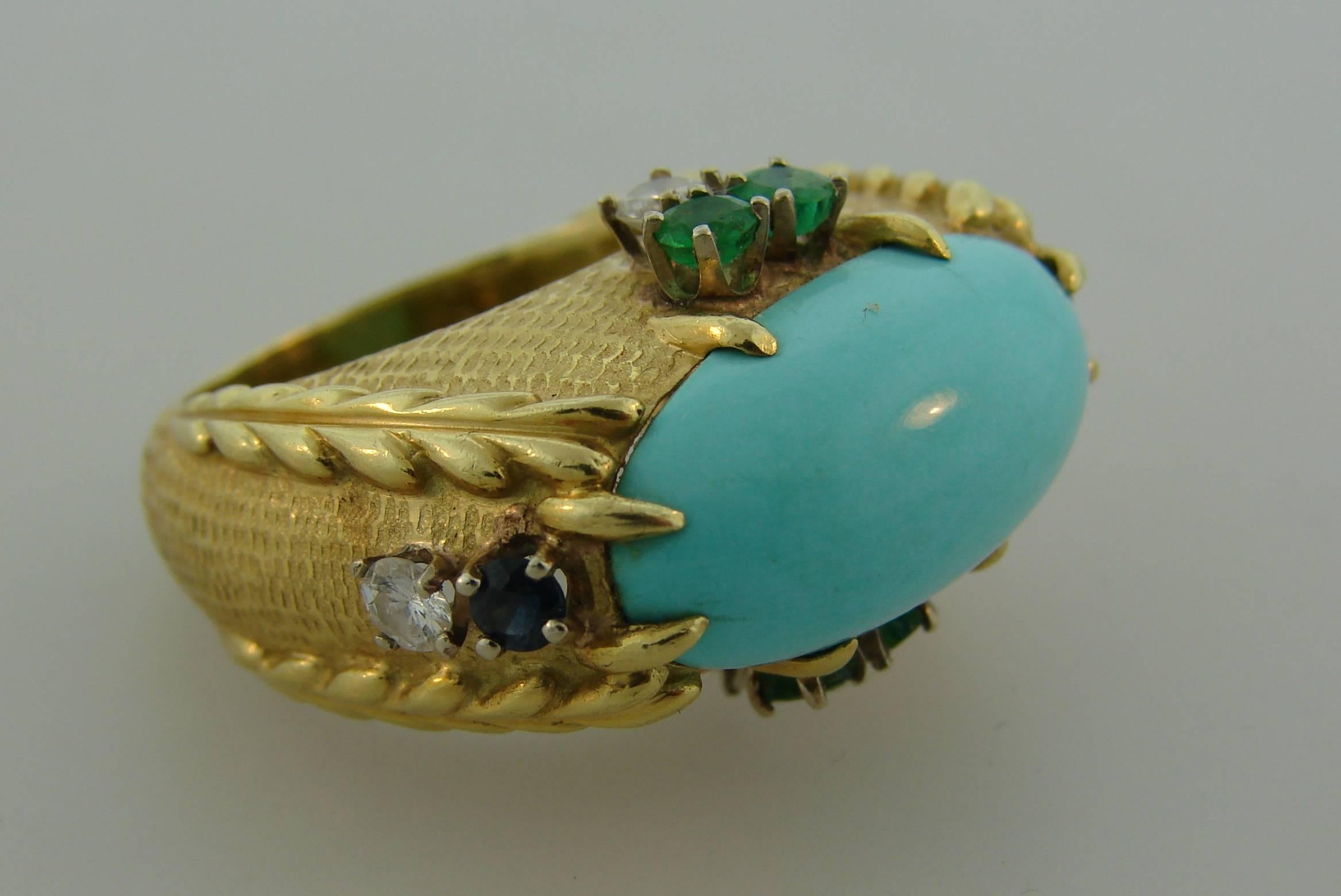 Stunning cocktail ring created by Cartier in New York in the 1970's. It features a beautiful oval-shaped Persian turquoise set in 18 karat yellow gold and accented with round brilliant cut diamonds, round faceted emeralds and sapphires. Unusual