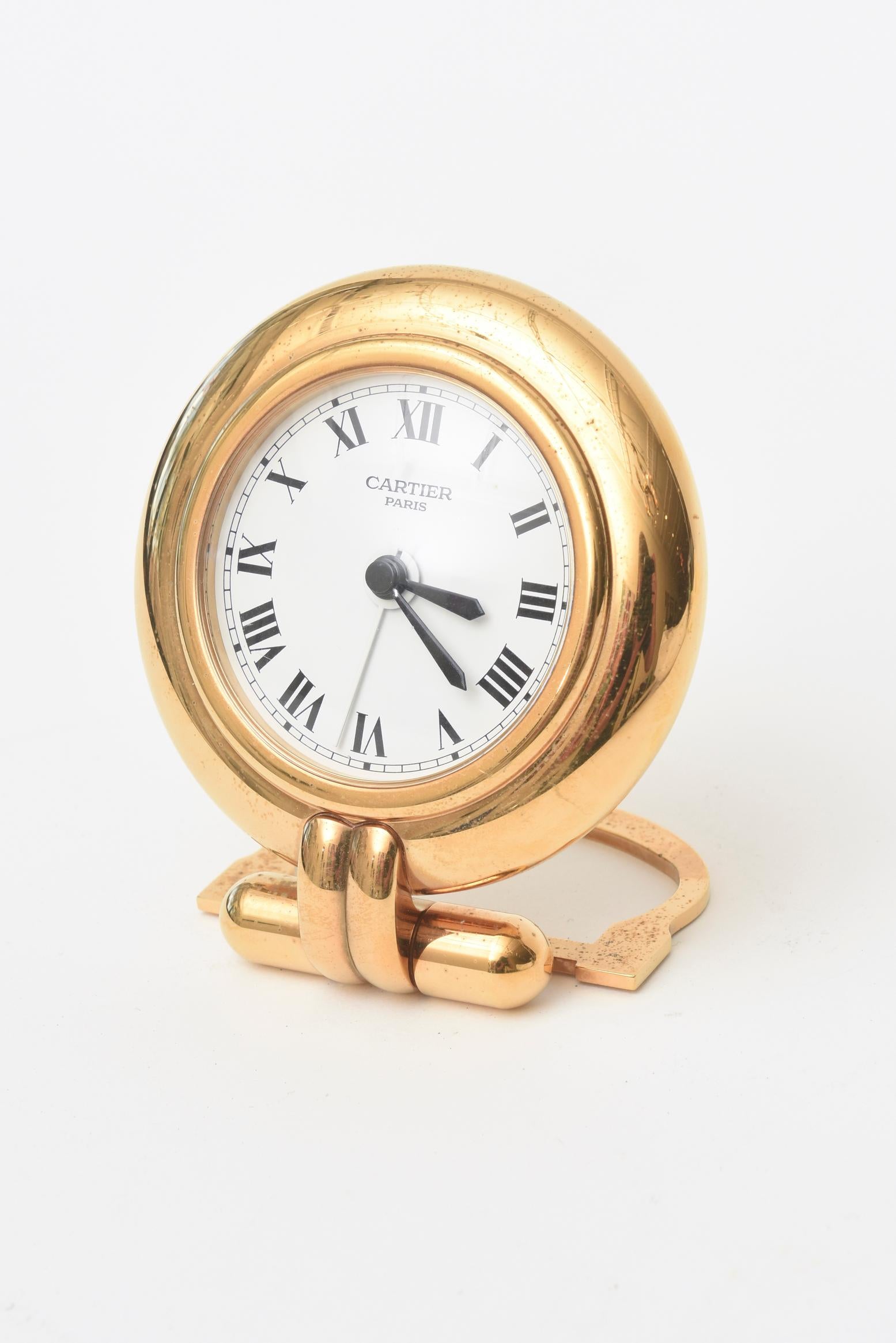 This regal hallmarked Cartier 24-karat gold-plated and lapis lazuli quartz travel or desk clock is no longer being made. It is from the 1990s. It was originally designed in the 1920s. It is marked Cartier made in France and numbered 0517789. The