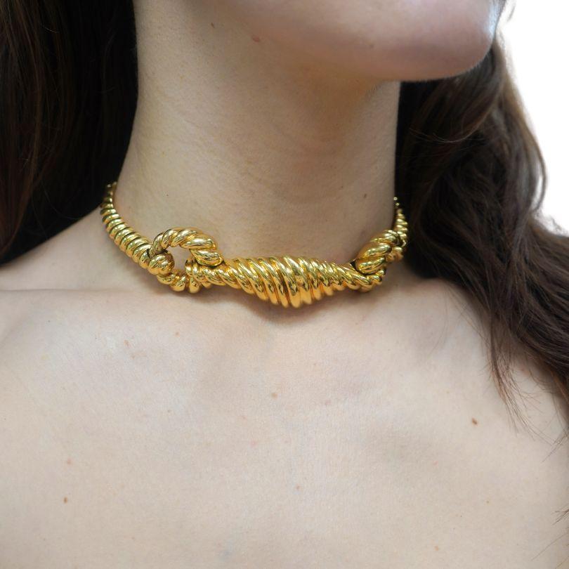 This is a choker necklace designed by Aldo Cipullo for Cartier, crafted in 18k yellow gold and dating back to the 1970s. Measuring 13 inches in length and 7/8 of an inch in width, the piece has a substantial weight of 111.8 grams, making it a bold