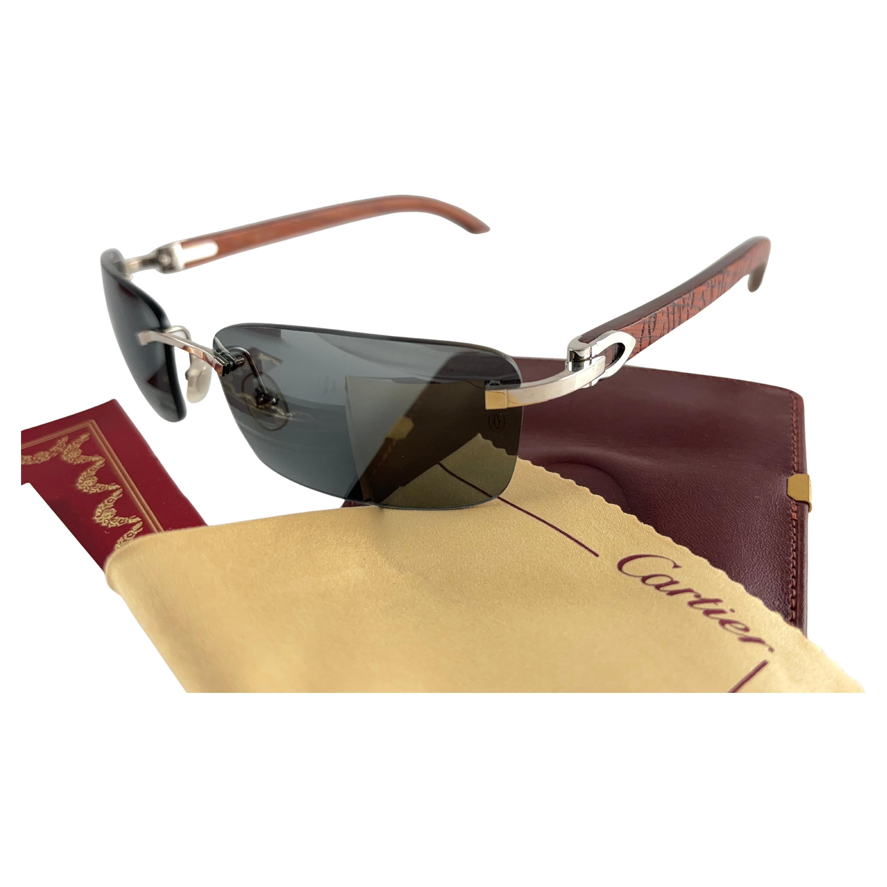Vintage Original Cartier Sunglasses with carved wood temples and solid grey uv protection lenses.  
Frame with the front and sides in platine.  
All hallmarks.  Platine Cartier signs on the ear paddles. 
Both arms sport the c from Cartier on the