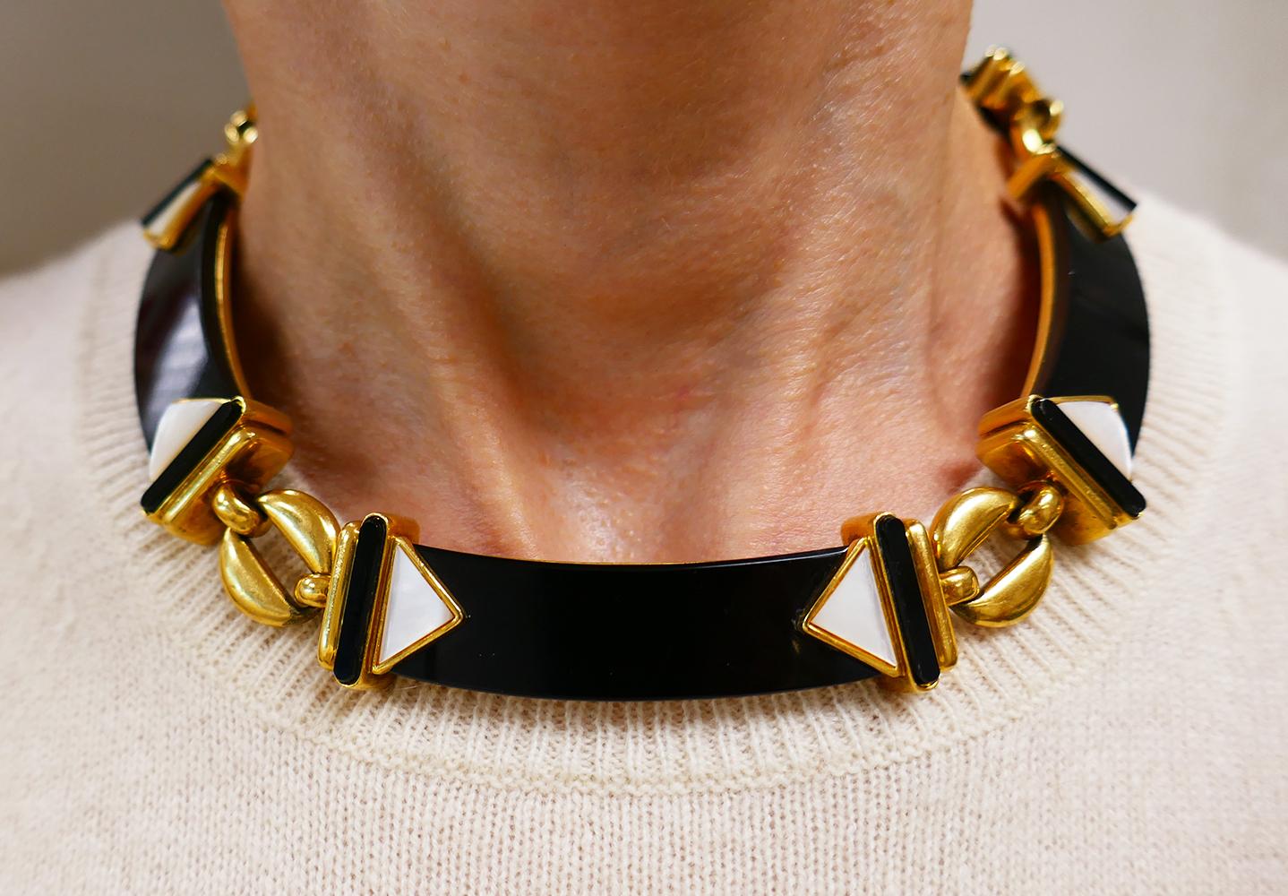 A gorgeous Cartier vintage necklace made of 18k yellow gold, black onyx, and mother-of-pearl.
The necklace design is unique and perfectly executed. It’s crafted as a flat choker comprising five rectangular black onyx plaques, slightly bent to create