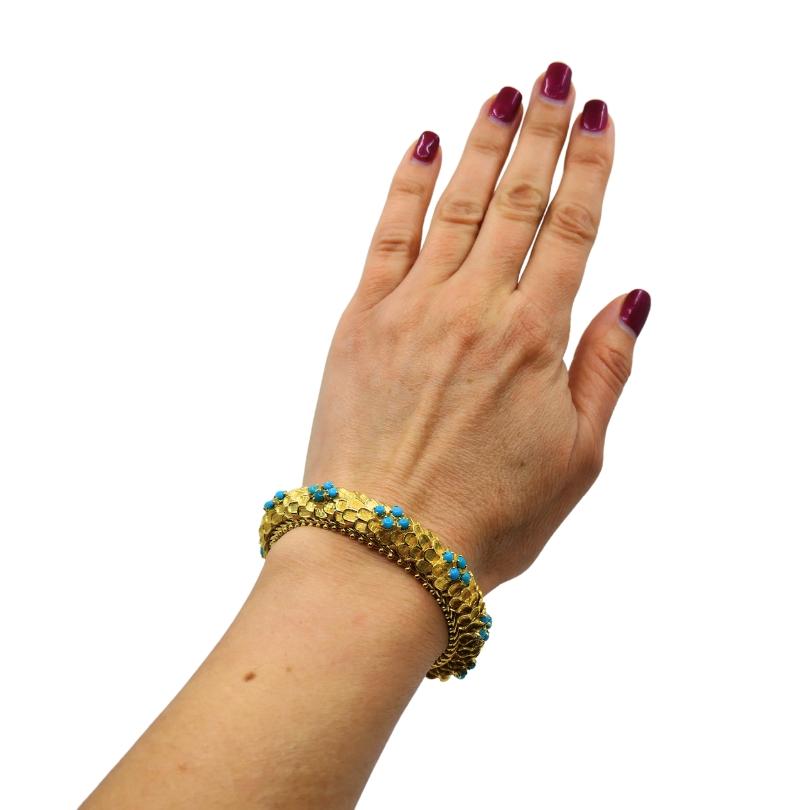 Vintage Cartier bracelet 18k gold features turquoise.
The bracelet’s delicate design consists of the layers of the gold scales. Alternating rows of turquoise beads set are arranged in a flower like pattern. This Cartier bracelet with a classic