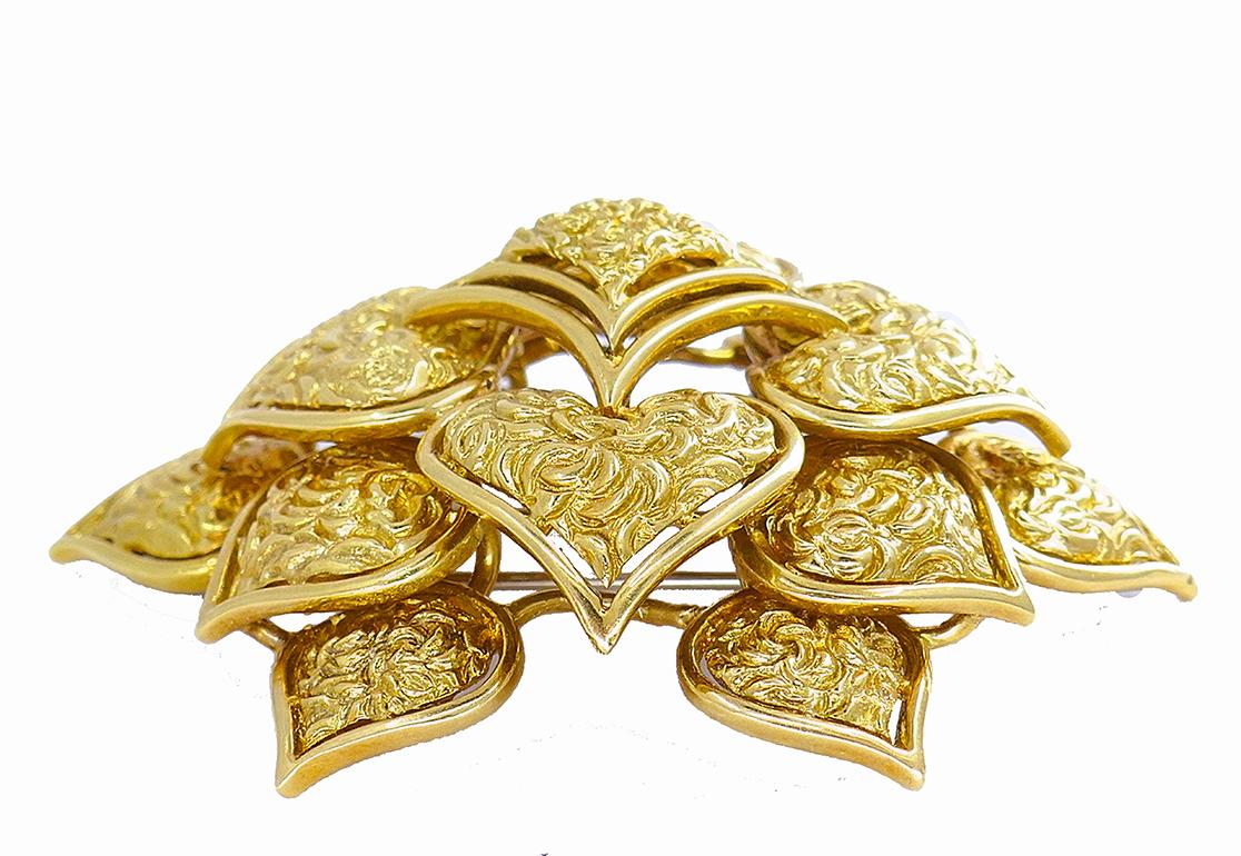 A lavish vintage Cartier brooch of a flower design, made of 18k gold.
This exuberant flower was created by layering together heart-shape gold petals to create a three-dimensional effect. Each petal is generously covered with a whimsically hammered