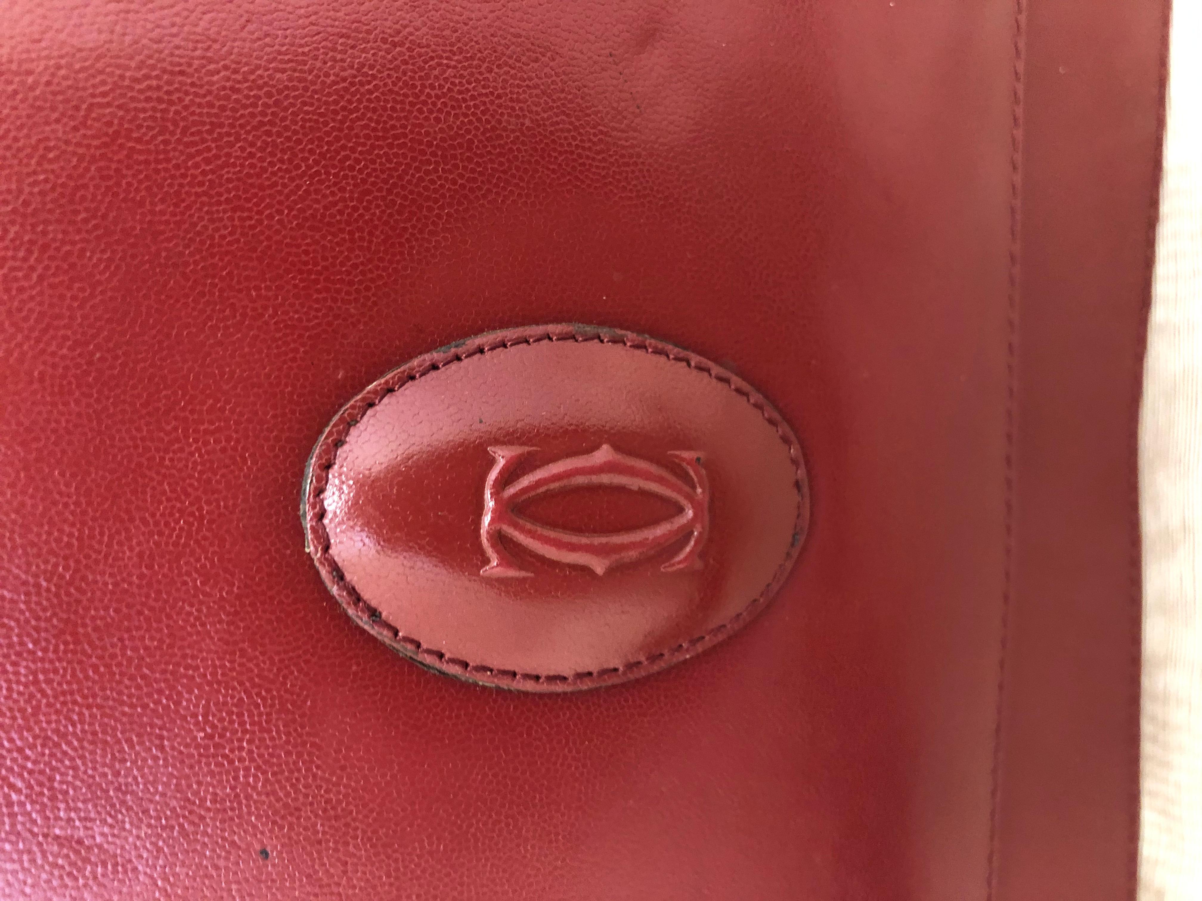 Made in France, this Cartier handbag is in excellent condition, with only a slight depression mark on the front (pictured). This handbag has a flap closure, adjustable strap and inside storage pockets. There is a nice Cartier medallion on the front,
