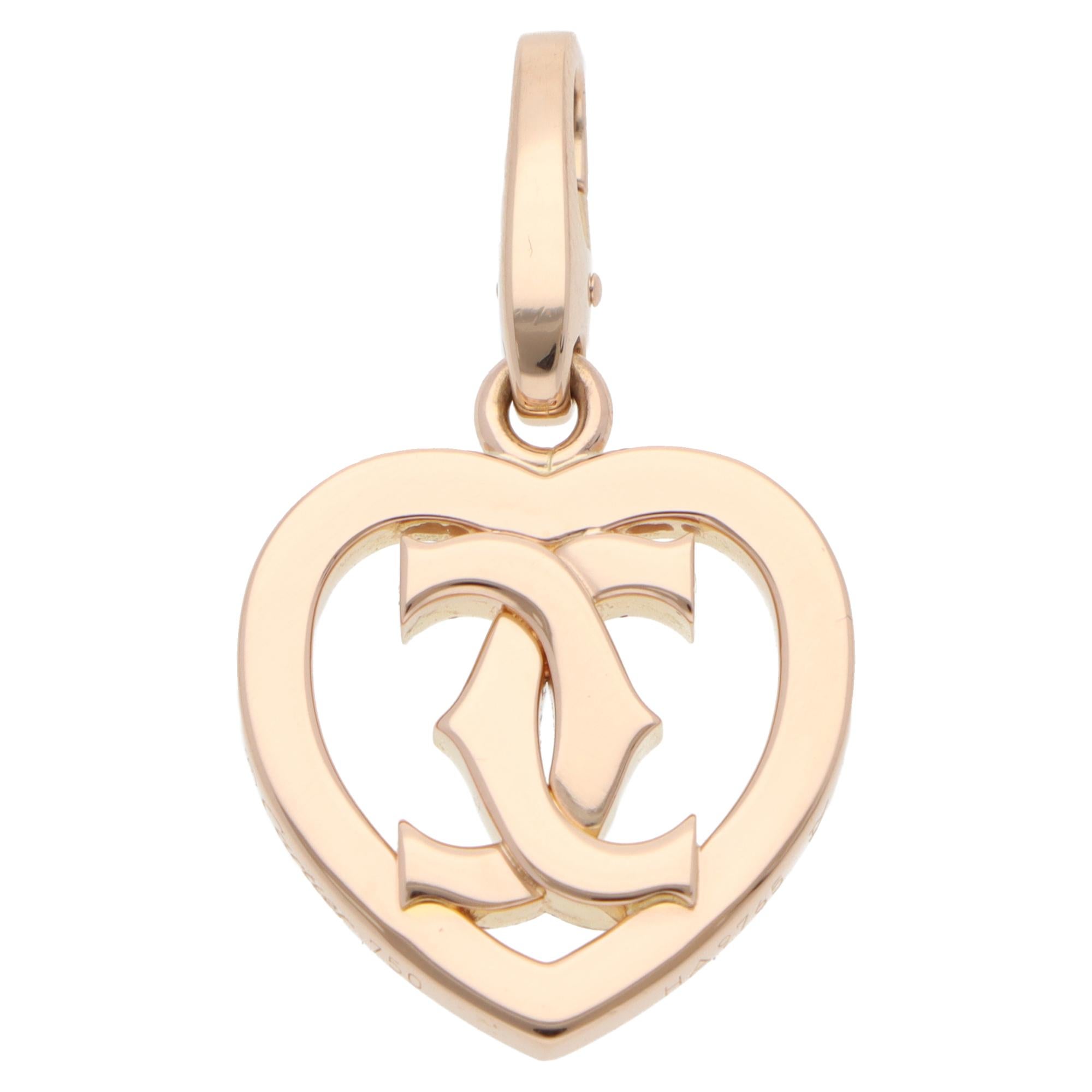 A beautiful vintage Cartier C de Cartier heart charm set in 18k rose gold.

The charm is composed of a solid rose gold heart with Cartier's iconic double C motif. It is securely connected to a bail, which can be opened from the back. The design
