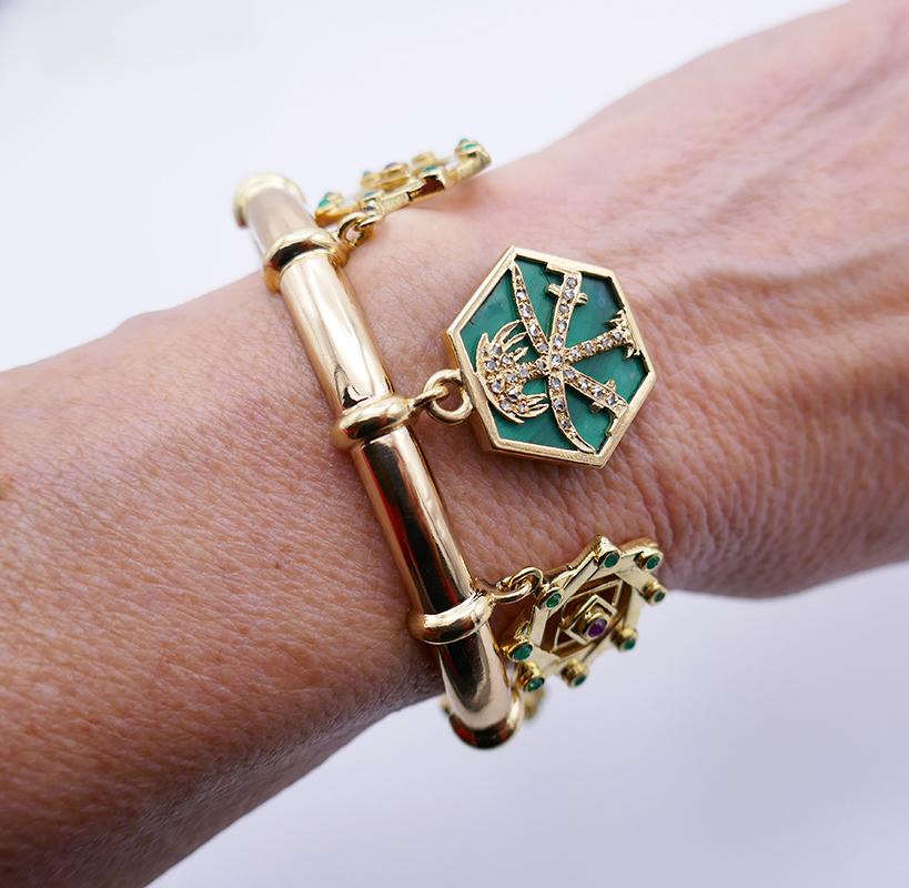            A rare vintage Cartier charm bracelet, made of 18 karat yellow gold, featuring gemstones. 
           The vintage bracelet has six charms in total. Two charms of a hexagonal shape feature malachite inlay adorned with the gold palm tree