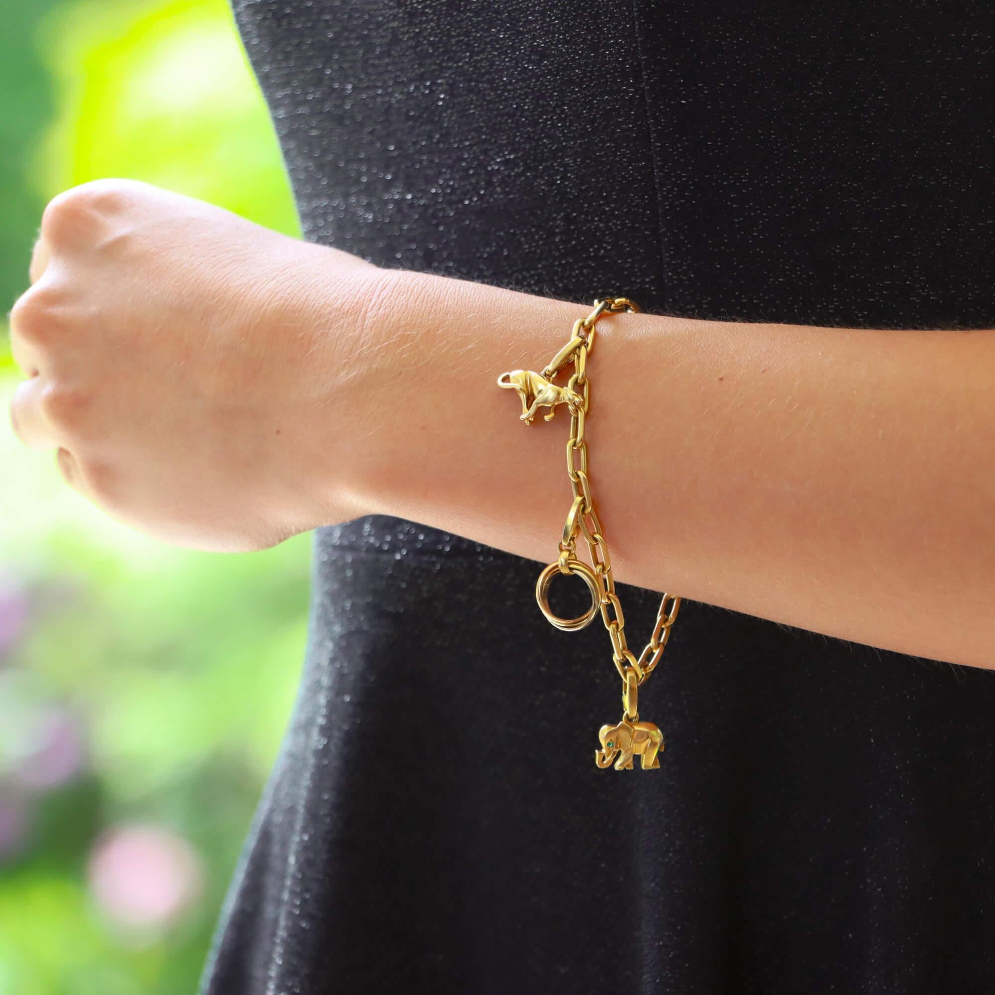 A beautiful vintage Cartier charm bracelet set in 18k yellow gold.

The piece is firstly composed of an elegant link bracelet, fastened with a secure lobster clasp with the Cartier logo stamped to one side. From this link bracelet hangs four