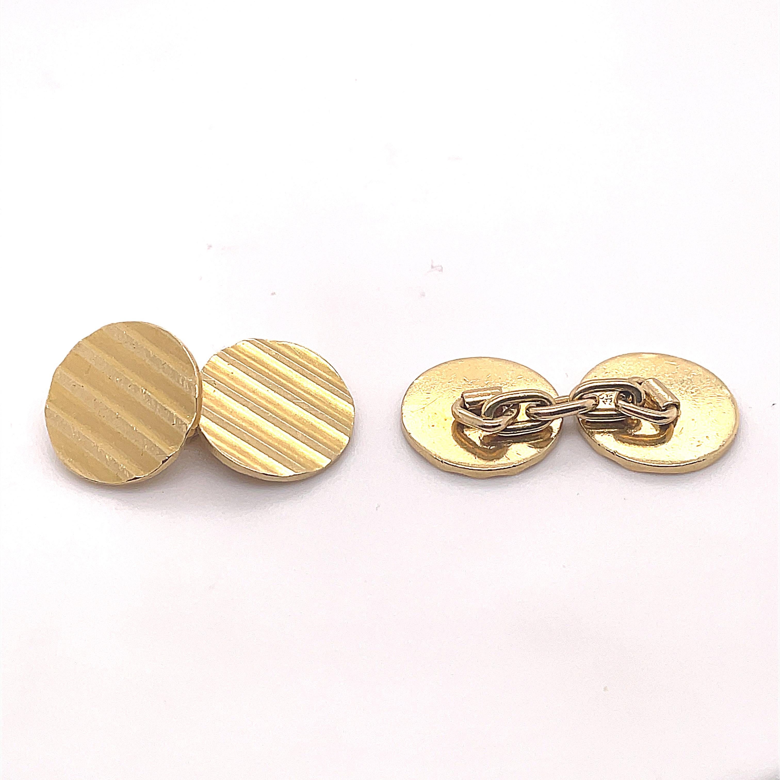 A pair of vintage Cartier cufflinks in 18 karat yellow gold, circa 1960.

This classic set of cufflinks are each designed as a matching pair of gold circles with textured ridged detail. The chain link fittings between the circles mean that these are