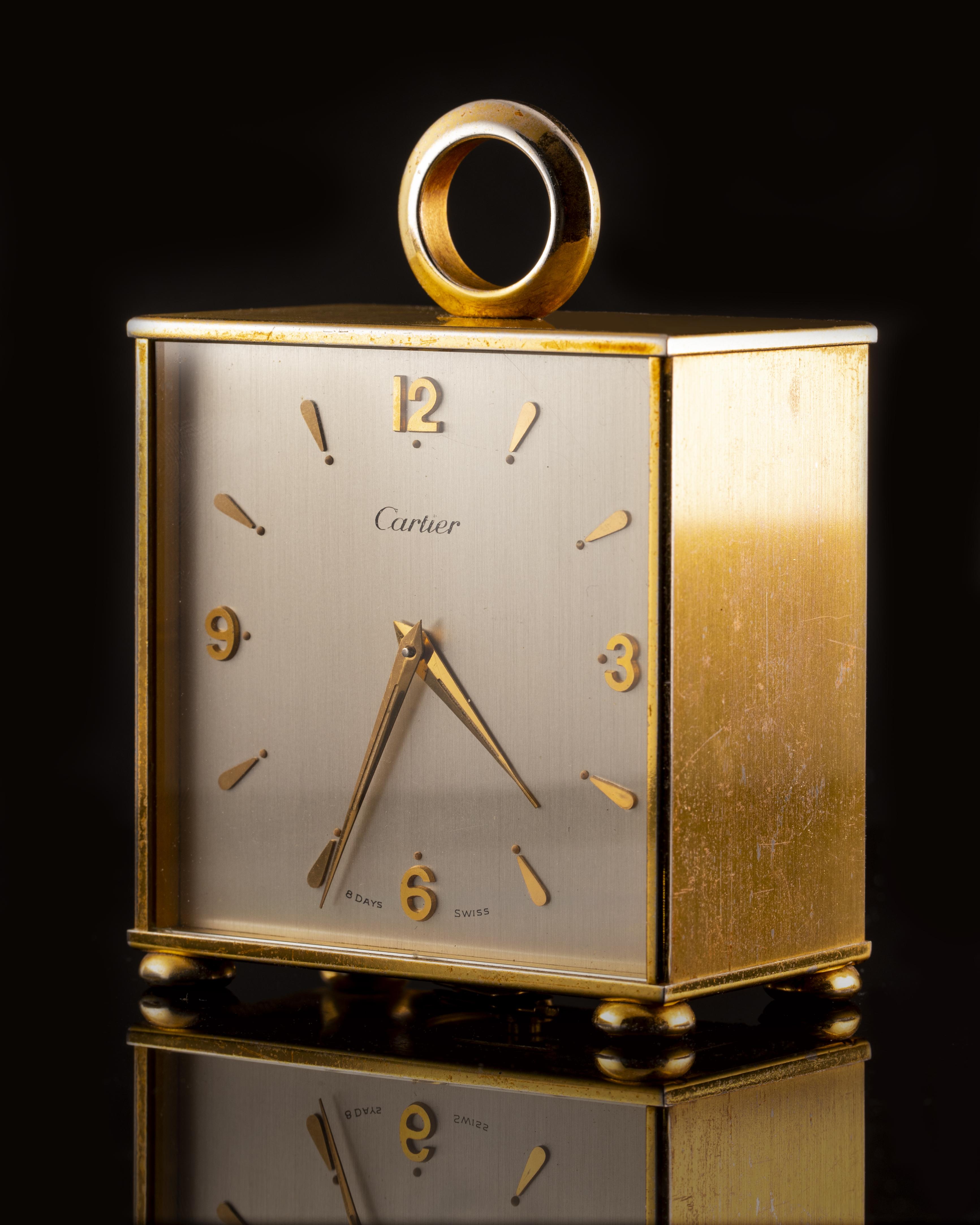 This authentic Cartier square shaped desk clock is made in gold brass N°304 with a double silver color dial with applied yellow brass indexes and dauphine hands. The mechanic movement was produced by Cartier N° 17460. Manual winding with crown
