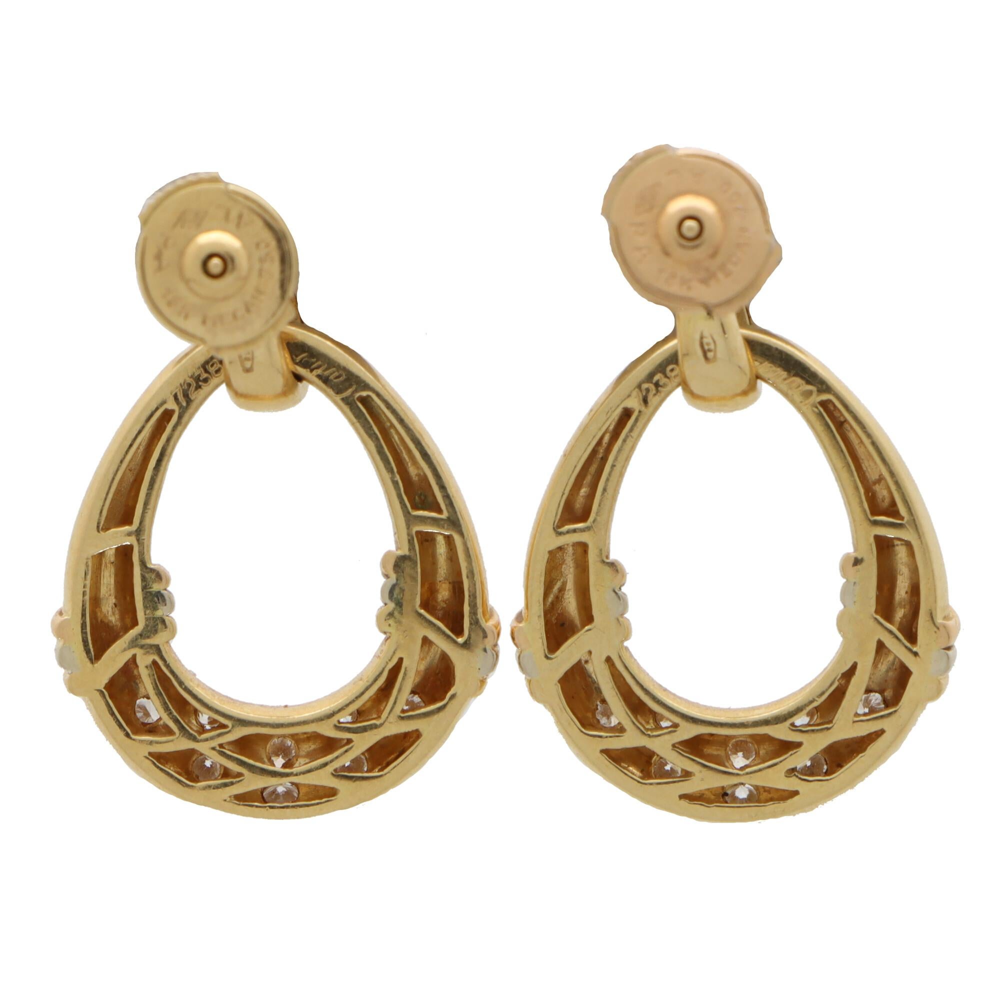  A beautiful vintage pair of Cartier diamond door knocker dangle earrings set in 18k yellow gold.

Each earring is composed of a graduating diamond set bail which hangs a doorknocker hoop. The hoop is set to each side with trinity bands and accented