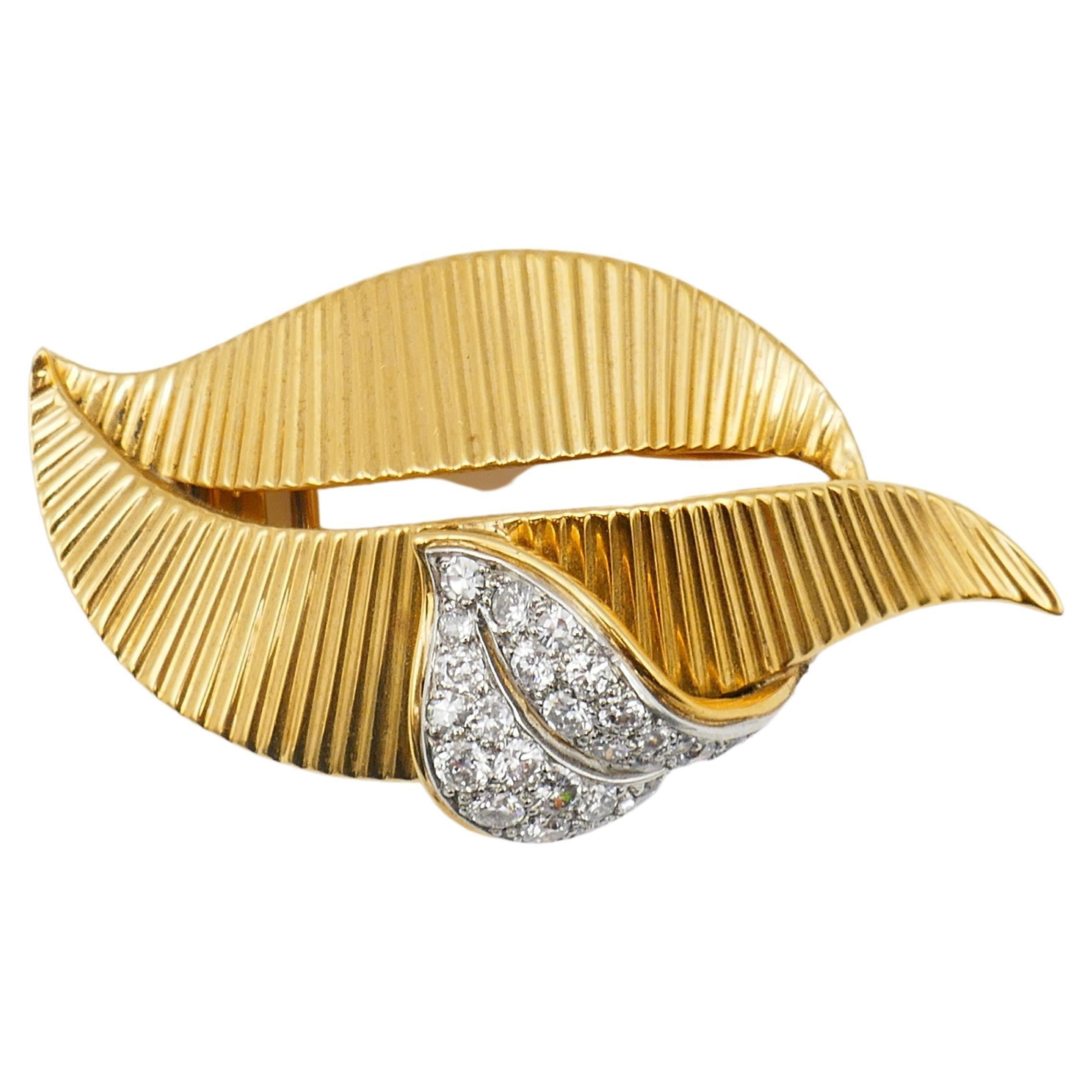 Vintage Cartier brooch made of 18k gold, featuring diamond.
A leafy motif comprises of two ribbed gold elements. A part on top of the 