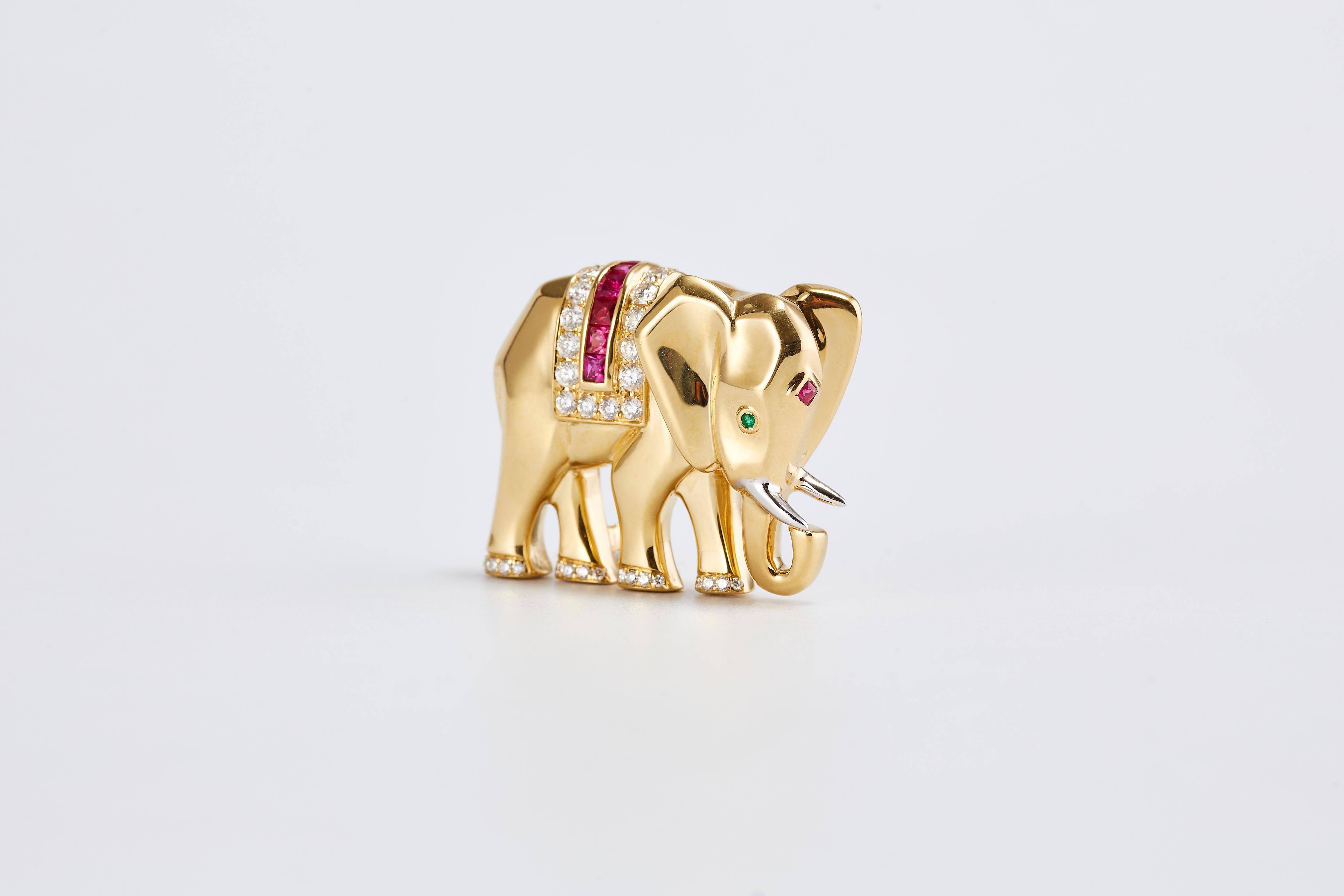 A vintage Cartier elephant pin/brooch in 18-karat yellow gold, with circular-cut emerald eye, and a ruby mark on the forehead.  Diamonds and ruby in the center of the pin and diamonds decorating the feet.
Circa 1990s. 
Total weight: 20.65 gr
