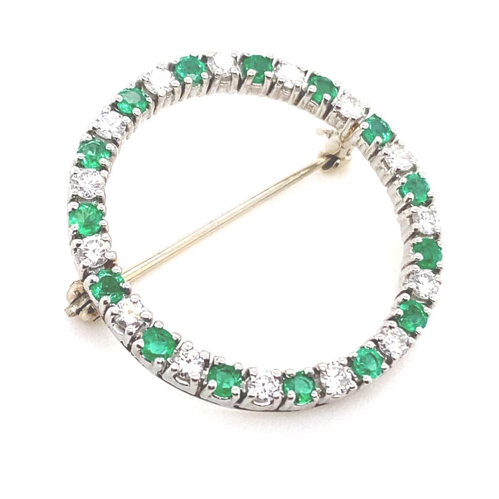 A vintage Cartier emerald and diamond platinum brooch, circa 1960.

Designed as a circle, claw set with alternating round brilliant cut diamonds and bright lively round cut emeralds.

The diamonds total 0.90 carats approximately, assessed as G/H
