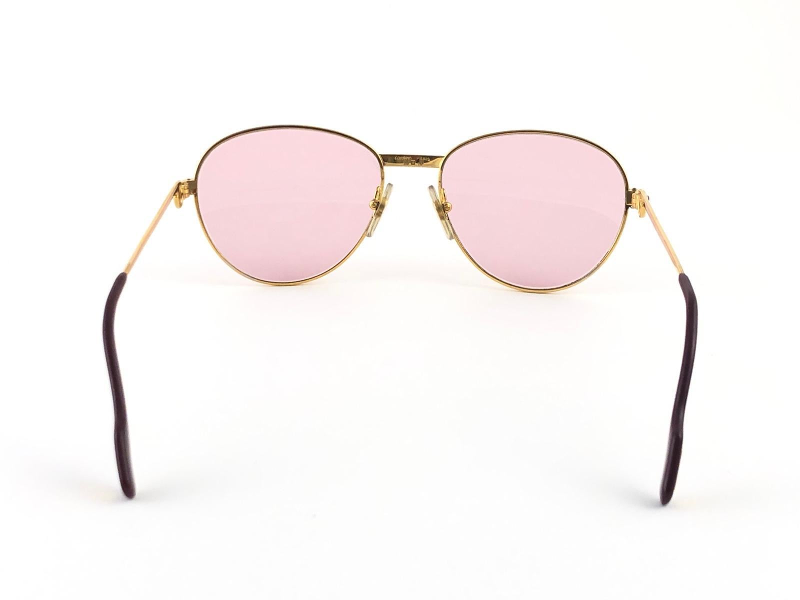 
In Excellent condition Cartier Louis rounded sunglasses with 2  rubies on the side of the frame. Light rose (uv protection) lenses. Frame is with the famous yellow and white gold accents on the front and on both sides. All hallmarks, from 1989. Red
