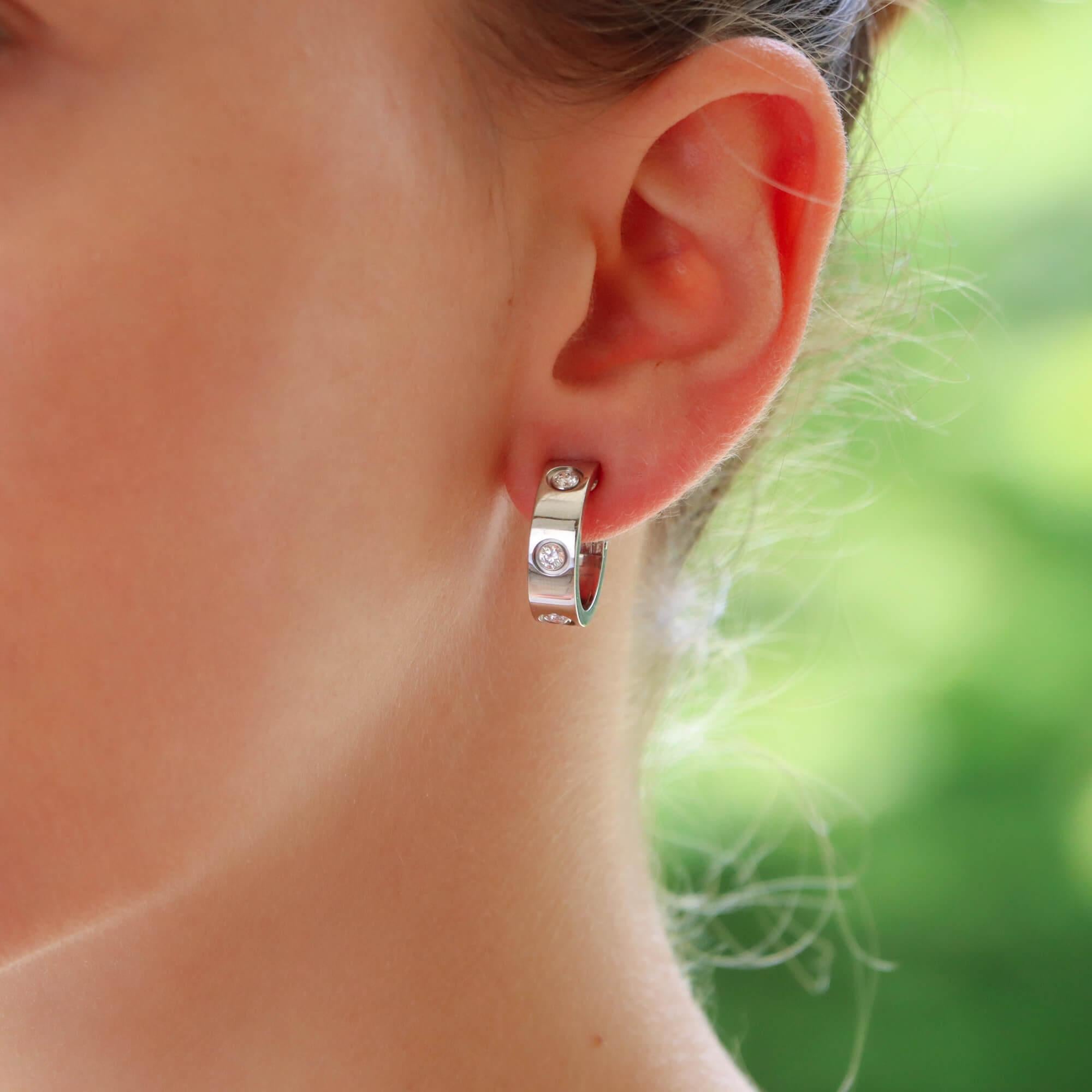 Paire de boucles d'oreilles classiques en or blanc 18 carats de Cartier, serties de diamants.

Les boucles d'oreilles sont serties du motif emblématique 