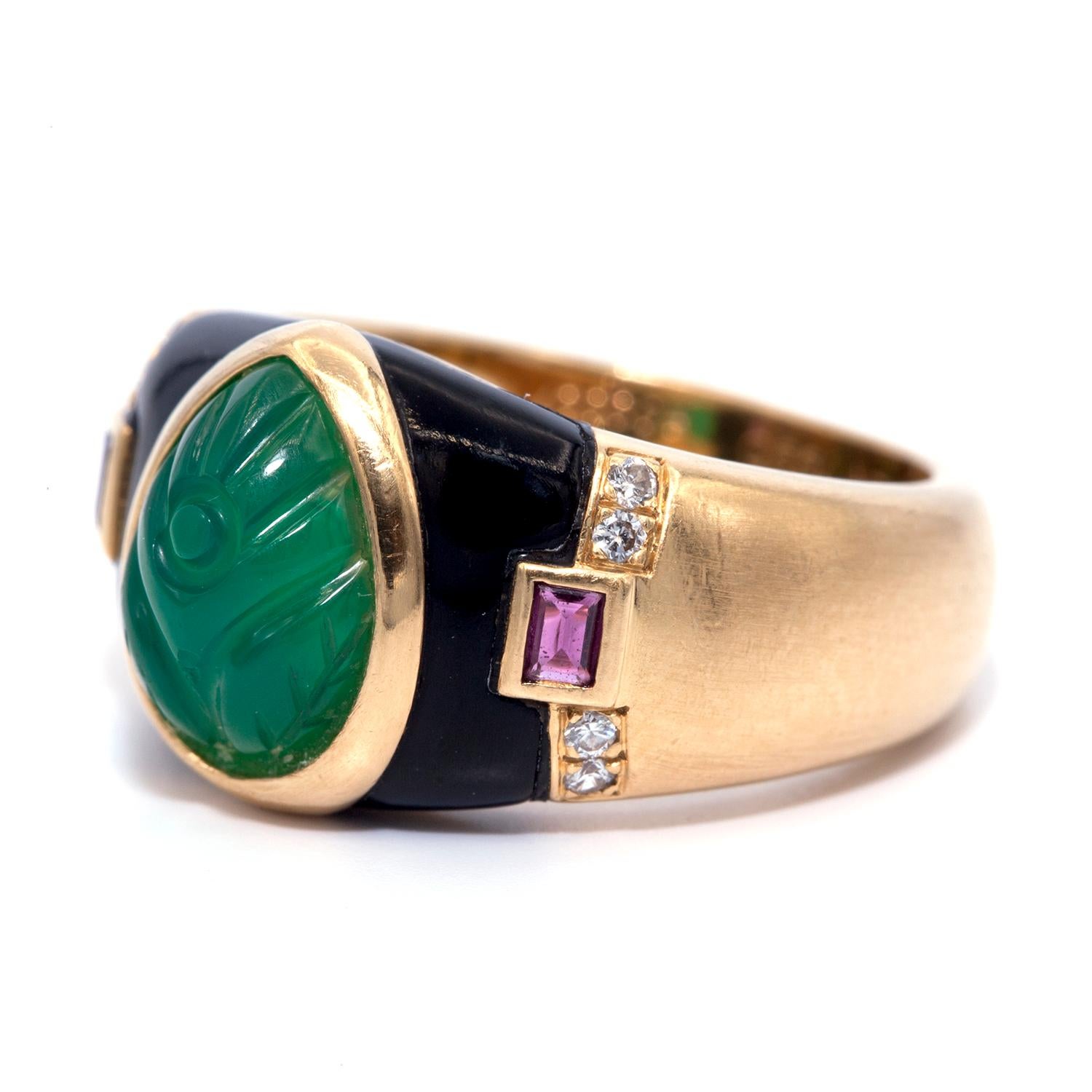 A Cartier true work of art.
the Gaia 18K yellow gold ring showcases a spectacular design. the ring shanks accented with onyx, rubies and approximately 0.04ct of diamonds.
The ring's main attraction is a carved emerald stone.
Ring Size: 5.5 
0.5cm
