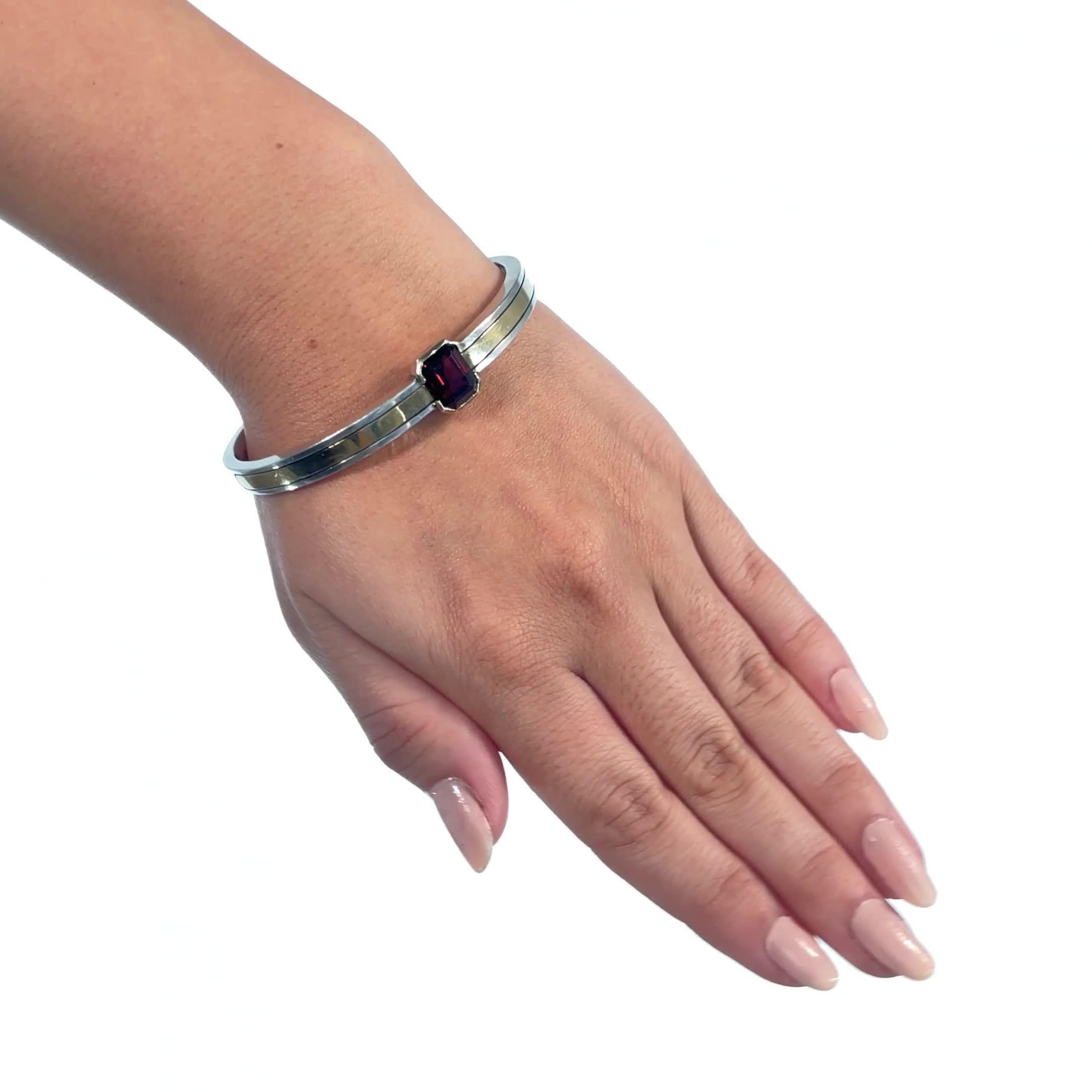 Vintage Cartier Garnet Silver Gold Bangle. Garnet is approximately 3.80 carat. Sterling silver and 18k gold, signed Cartier with purity marks. Circa 1980s. 

About The Piece: When it comes to Cartier, you can expect exquisite, exciting jewels for