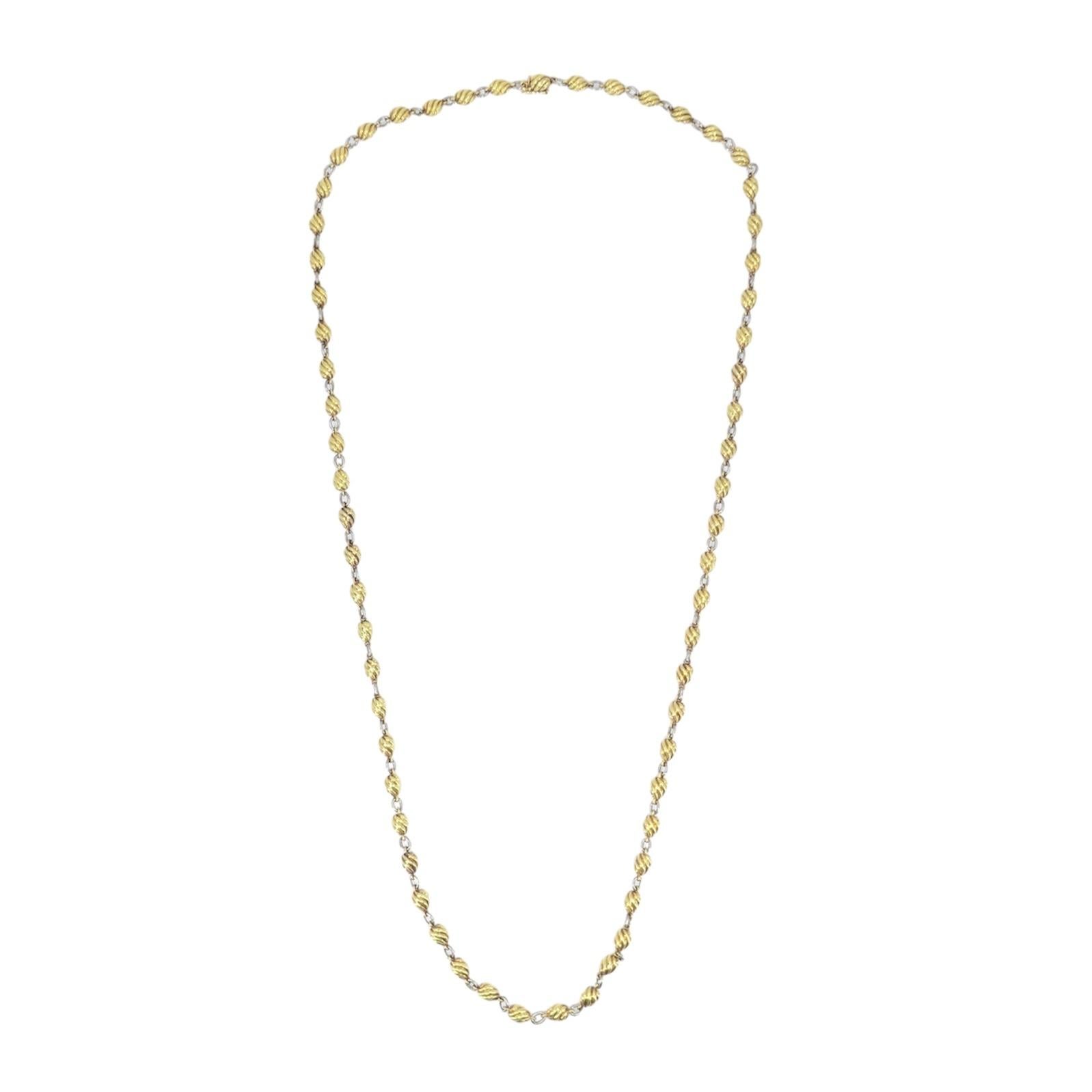 Questa elegante collana a catena di Cartier è realizzata in oro giallo e bianco 18 carati. Con una lunghezza di 28 pollici e una larghezza di 3/16 di pollice, presenta un caratteristico motivo a spirale a barile con perline ovali in oro giallo,