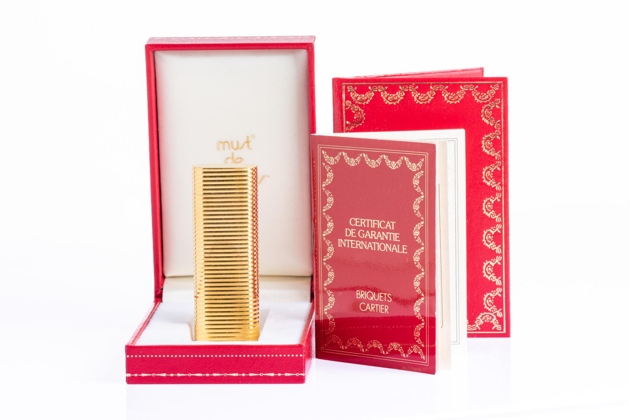 A classic Must de Cartier Paris lighter, finished in a striking gold-plated ribbed “Godron” design. Elegant and timeless, this lighter reflects Cartier’s iconic design language of the 1970s–1980s. Stamped with serial number: 0180X.

Details:
•