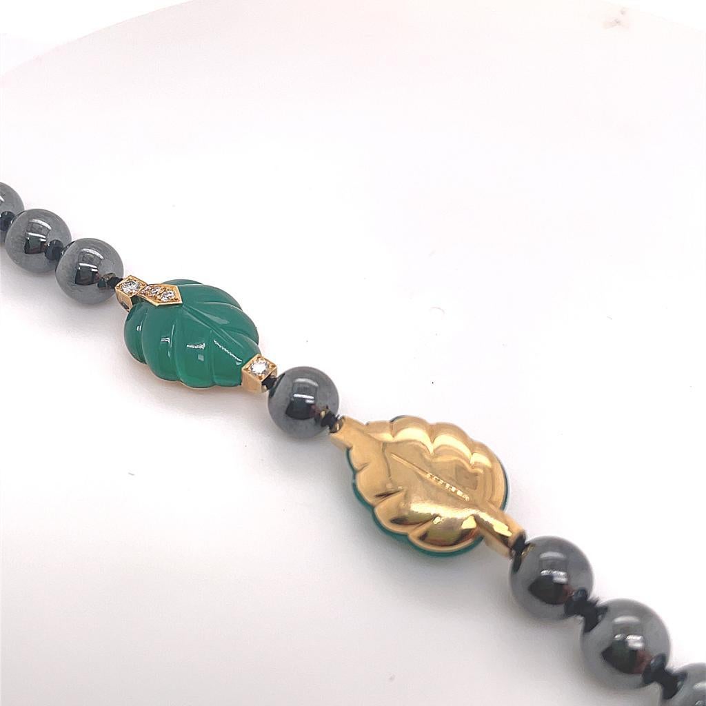A vintage Cartier hematite, chalcedony and diamond necklace in 18 karat yellow gold, circa 1990.

This beautiful necklace is designed as a row of round hematite beads which have an elegant and understated metallic lustre. Carved chalcedony leaves