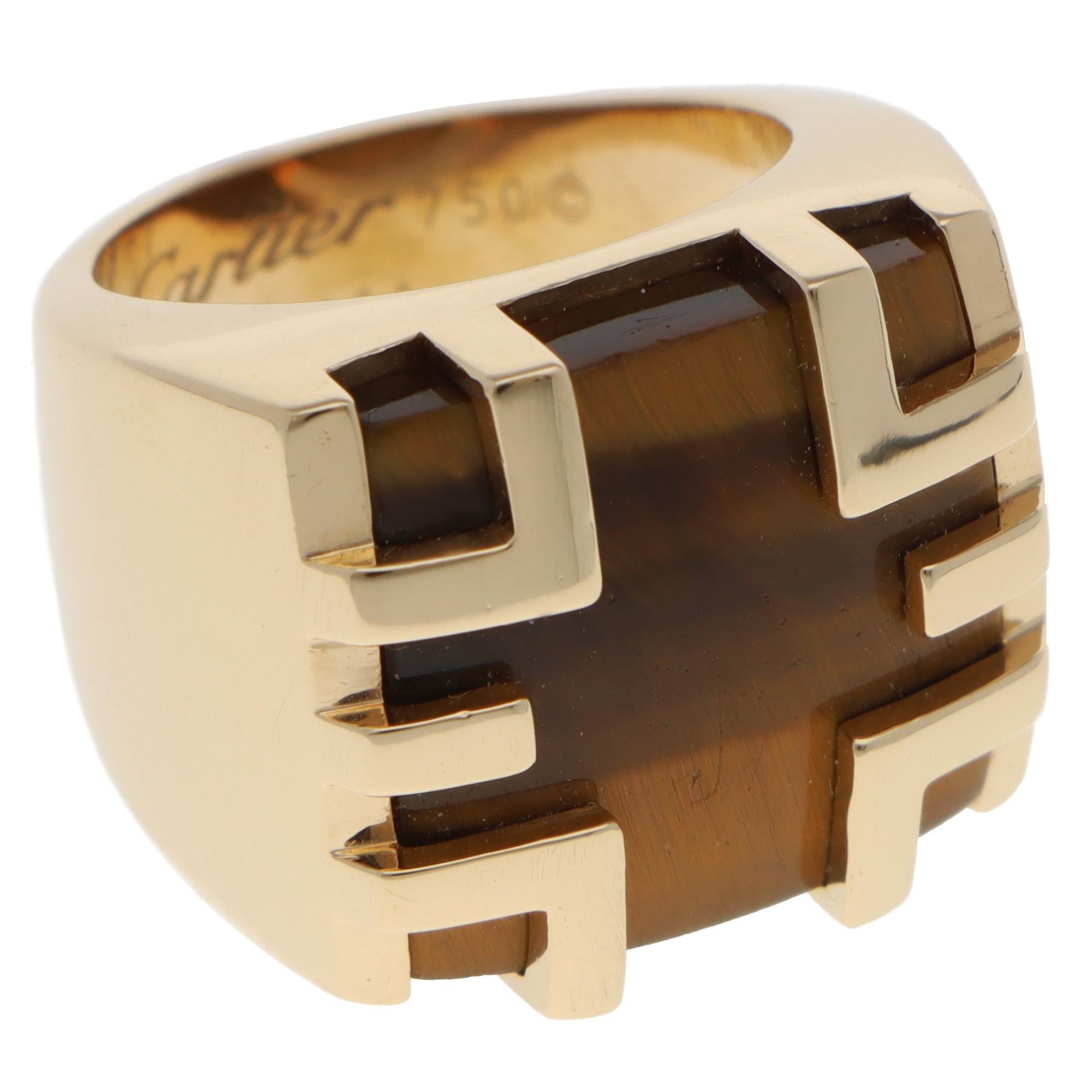 Eine schöne Vintage Cartier Le Baiser du Dragon Tigerauge Ring in 18k Gelbgold gesetzt.

Der Ring zeigt ein gelblich-braunes Tigerauge mit charmanter Chatoyancy-Optik. Die Reflexion des Tigerauges hebt sich schön auf dem Finger ab. Er ist in das