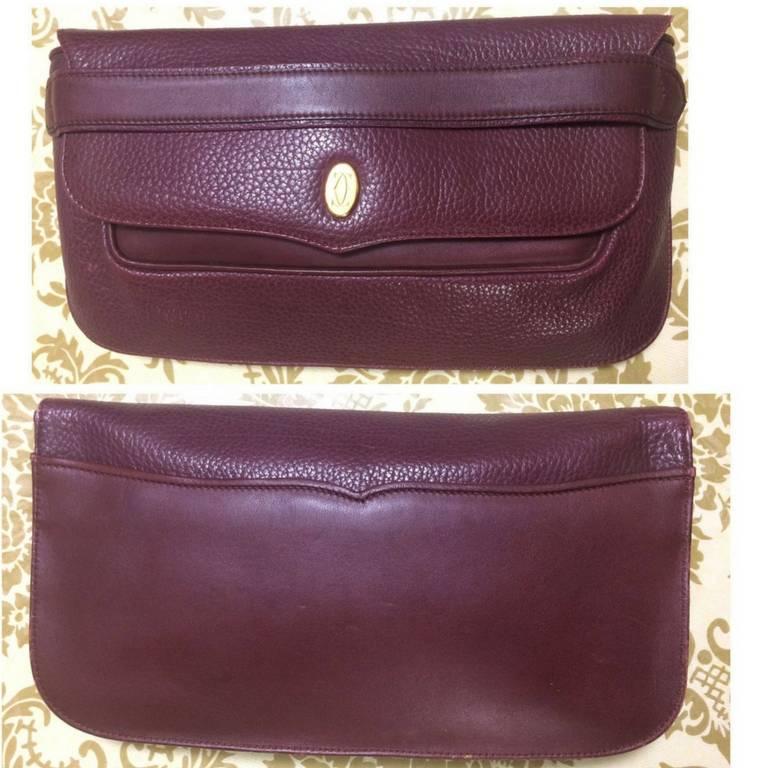 1990s. Vintage Cartier leather wine color clutch with gold tone charm. must de Cartier Collection.

This is a Cartier vintage purse from the 90's, must de Cartier collection. 
Classic wine leather purse would definitely be one of your vintage