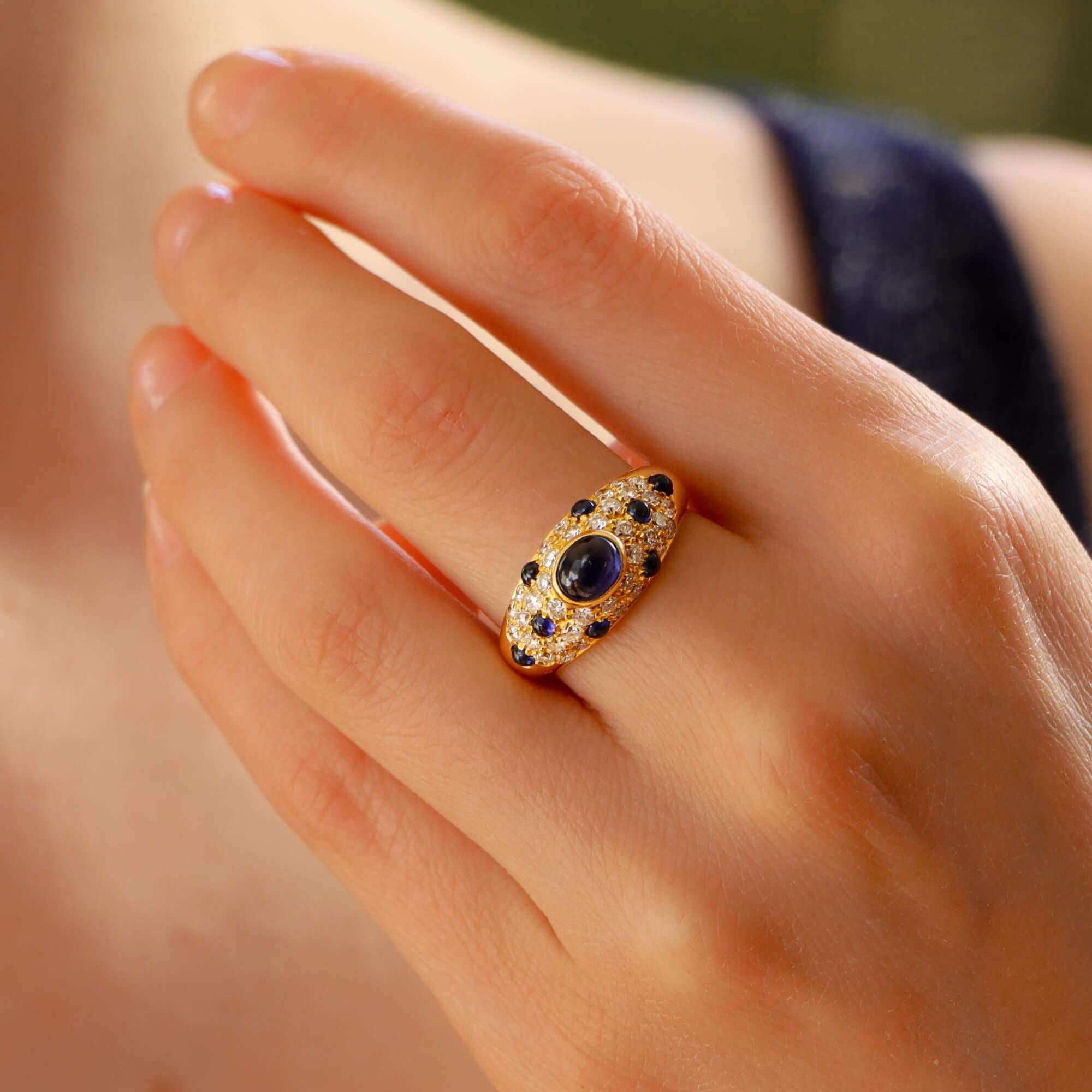 A beautiful vintage Cartier Mimi sapphire and diamond ring set in 18k yellow gold, circa 1990s.

From the discontinued Mimi collection, this ring predominantly features an oval cabochon blue sapphire, which is bezel set securely to the centre of the