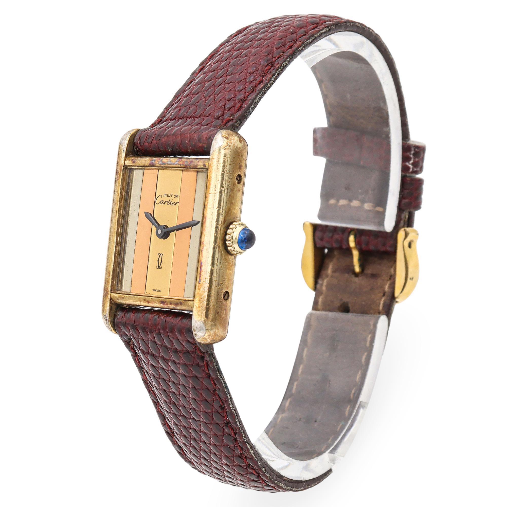 Diese elegante Must de Cartier Tank Armbanduhr strahlt Vintage-Luxus und zeitlosen Stil aus. Das rechteckige Vermeil-Gehäuse (Gold über Sterlingsilber) mit sanft abgerundeten Kanten hat ein markantes gestreiftes Zifferblatt mit abwechselnden