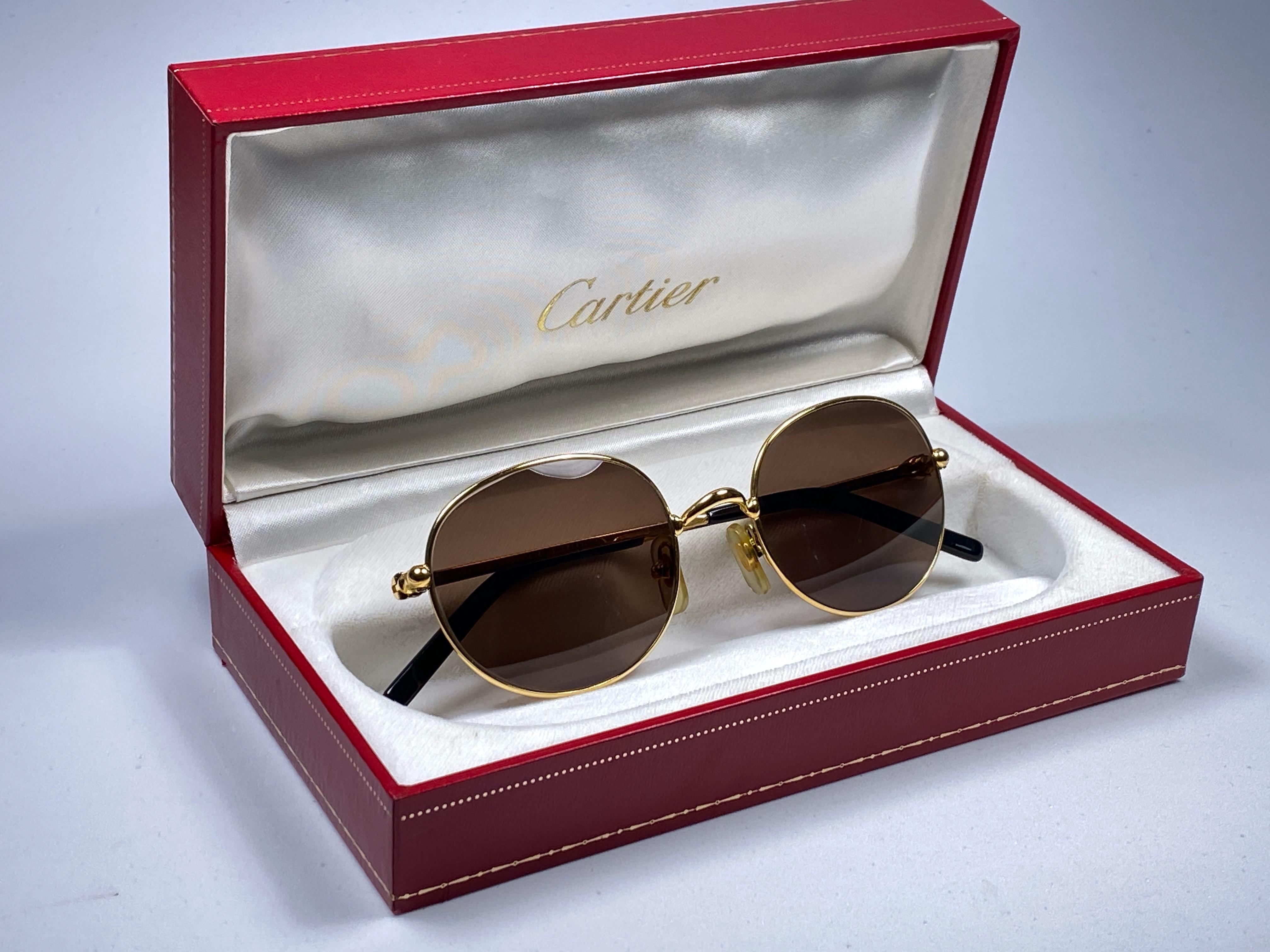 Lunettes de soleil Antares ovales de Cartier avec verres bruns (protection contre les UV).  Tous les poinçons. Signes Cartier en argent sur les palettes d'oreille. 
Les deux bras portent le nœud de Cartier sur la tempe. Ils sont comme une paire de