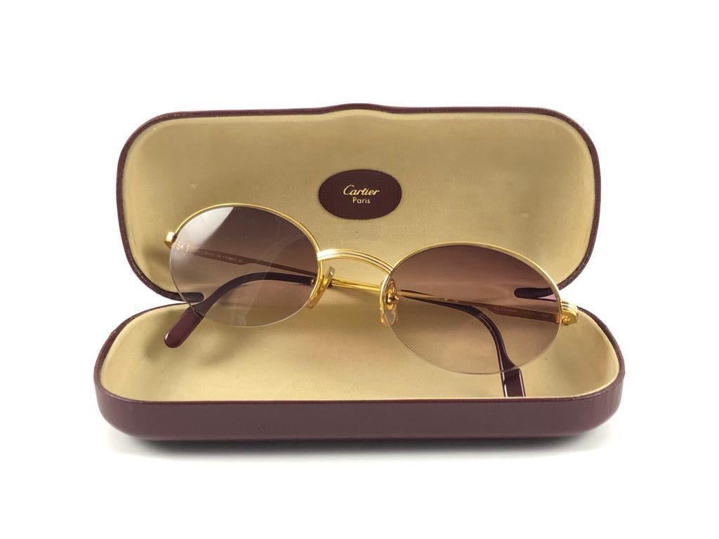 Vintage Cartier oval Manhattan sunglasses with mauve gradient lenses (uv protection).  All hallmarks. Gold Cartier signs on the ear paddles. 
Both arms sport the knot from Cartier on the temple. These are like a pair of jewels on your nose. 

Please