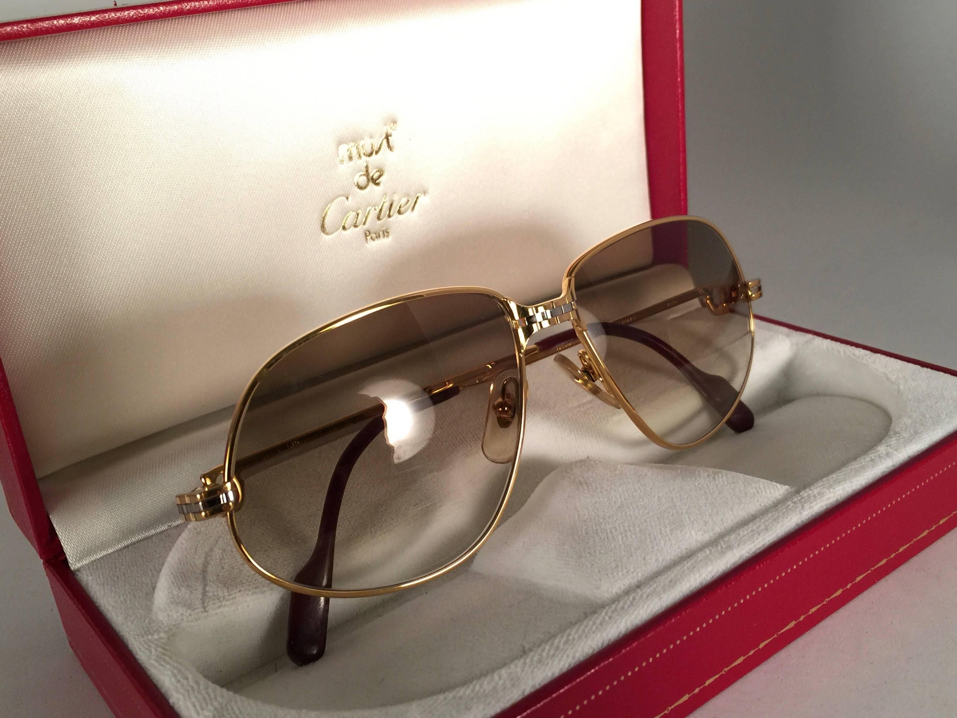 Vintage 1988 Cartier Panthere sunglasses with brown gradient (uv protection) lenses.  Frame is with the front and sides in yellow and white gold. All hallmarks. burgundy ear paddles. 
Both arms sport the C from Cartier on the temple. 
These are like