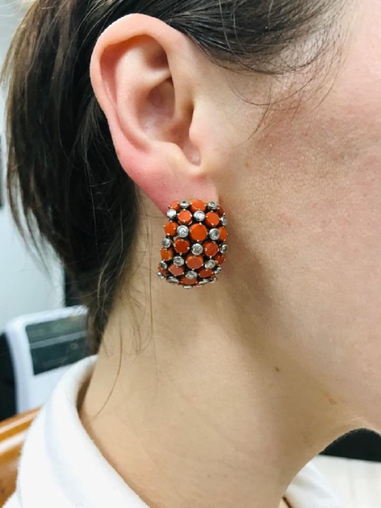 An amazing pair of vintage earrings by Cartier Paris made of 18k gold, featuring coral and diamonds. The gems on those huggie earrings are set in a quilted pattern. The diamonds are round cut, bezel set, while the corals, with the shape reminiscent