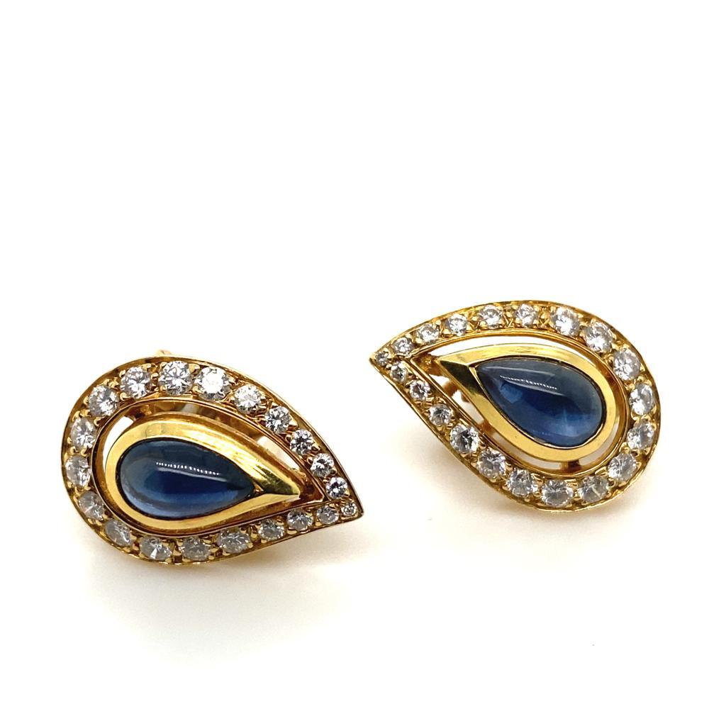 A pair of vintage Cartier Paris sapphire and diamond 18 karat yellow gold earrings, circa 1980.

These elegant cluster earrings are set to the centre with pear shaped cabochon sapphires for a total weight of 3 carats approximately, within a