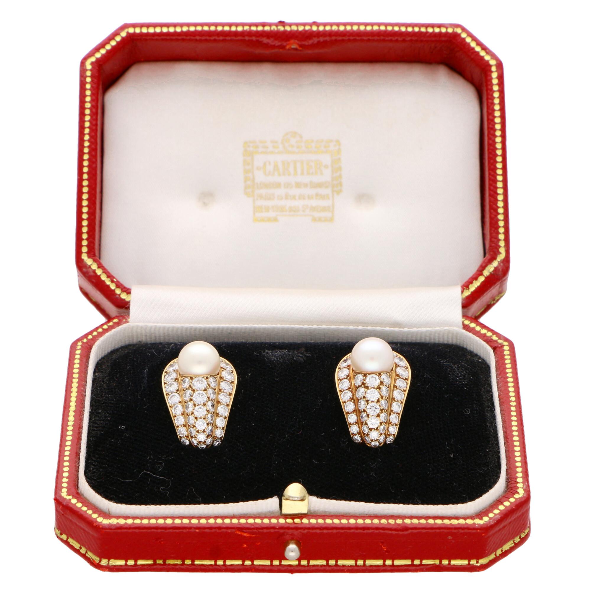 A truly beautiful pair of vintage Cartier pearl and diamond earrings set in 18k yellow gold. 

Each earring is centrally set with a beautiful lustrous 8-8.5 millimetre cream colored pearl. These pearls are each set within a cluster formed of 37