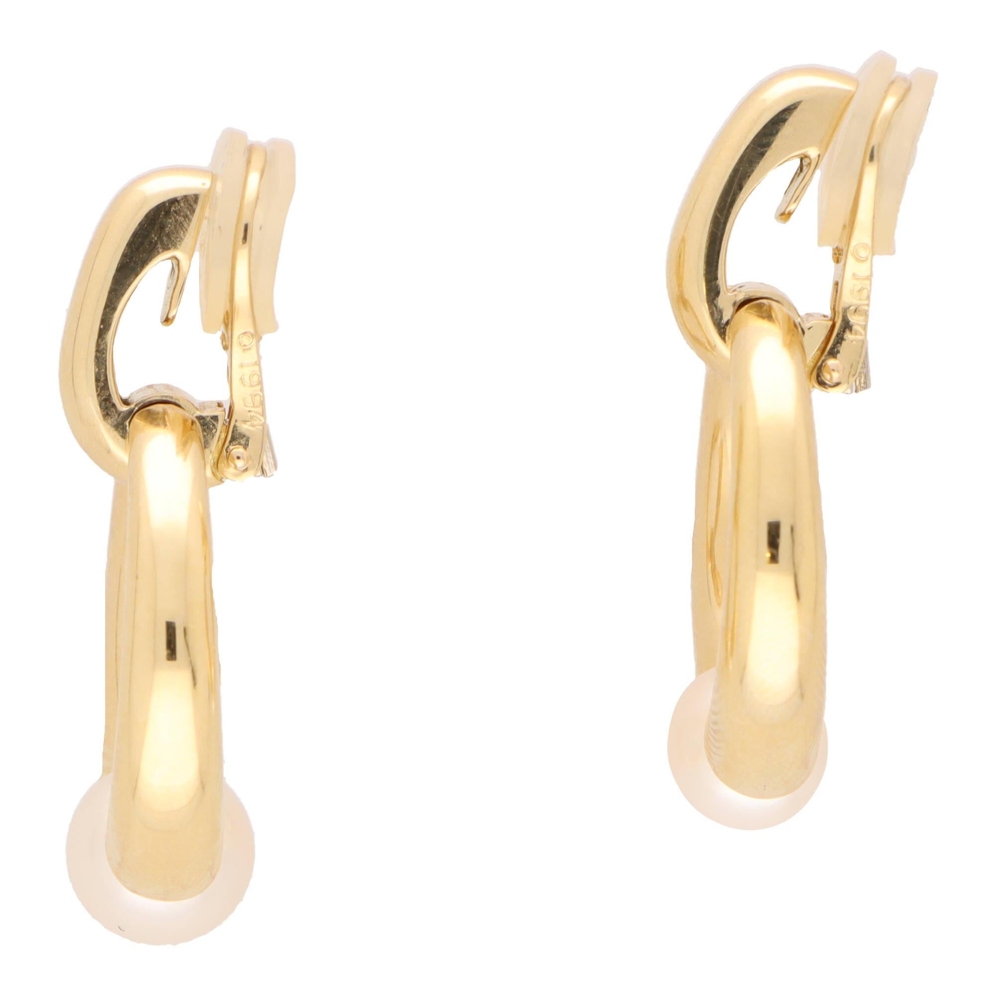 A stylish pair of vintage Cartier door knocker style pearl earrings set in 18k yellow gold.

Each earring is composed of an openwork circular motif set with 8-millimetre cultured pearl. The circular motif hangs from a yellow gold half hoop design