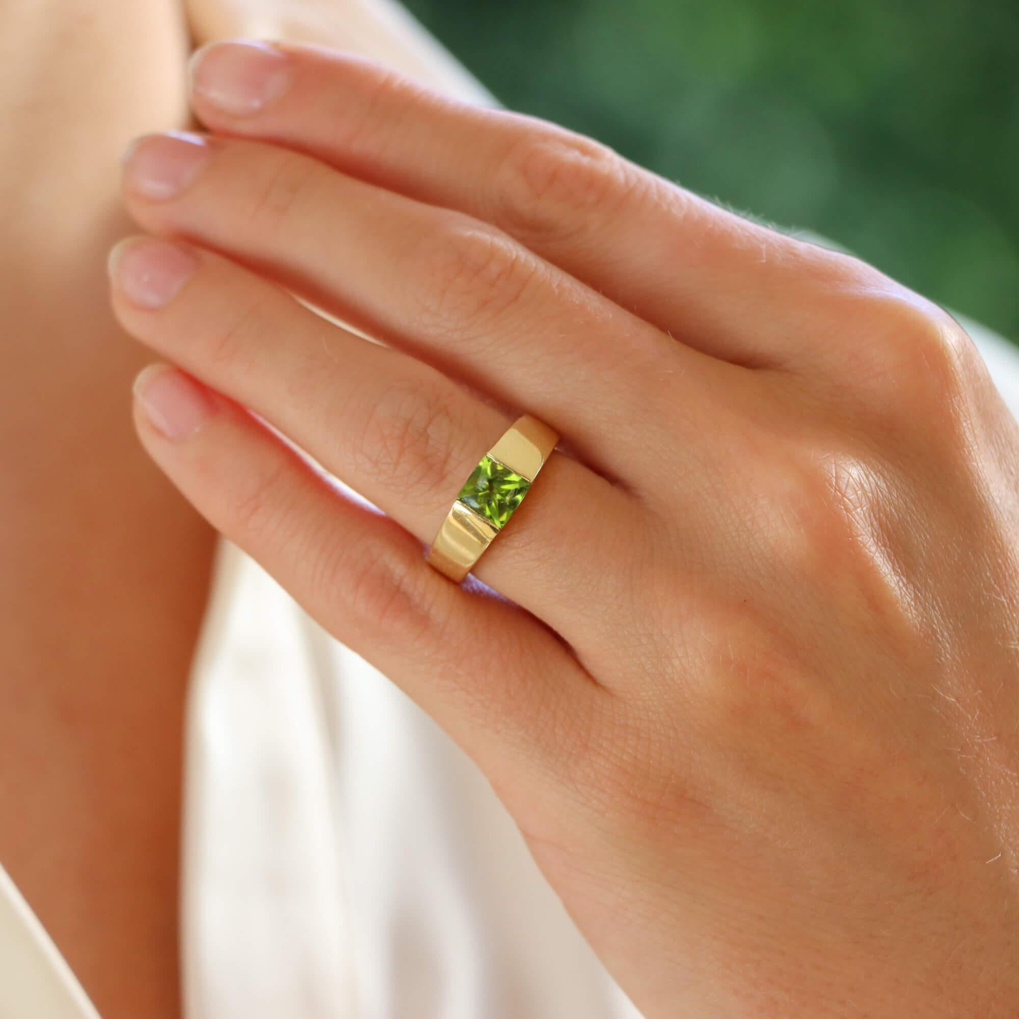 A vintage Cartier peridot tank ring set in 18k yellow gold.

The ring is solely set with a square cut piece of peridot, bezel set securely to centre. The head of the ring is slightly raised with polished white gold shoulders that flow round nicely