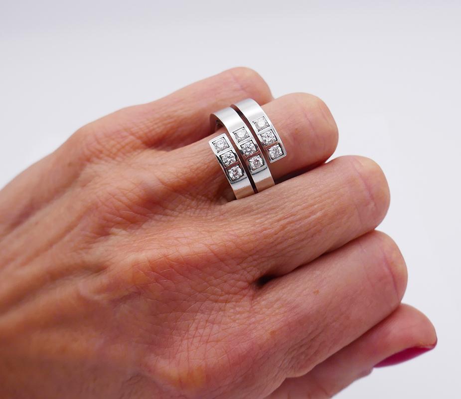 A vintage Cartier ring in 18 karat white gold, featuring nine round brilliant cut diamonds.
It’s a spiral cocktail ring designed as a triple wrap-around white gold band. Three rows of diamonds are staged in the center of the ring in square