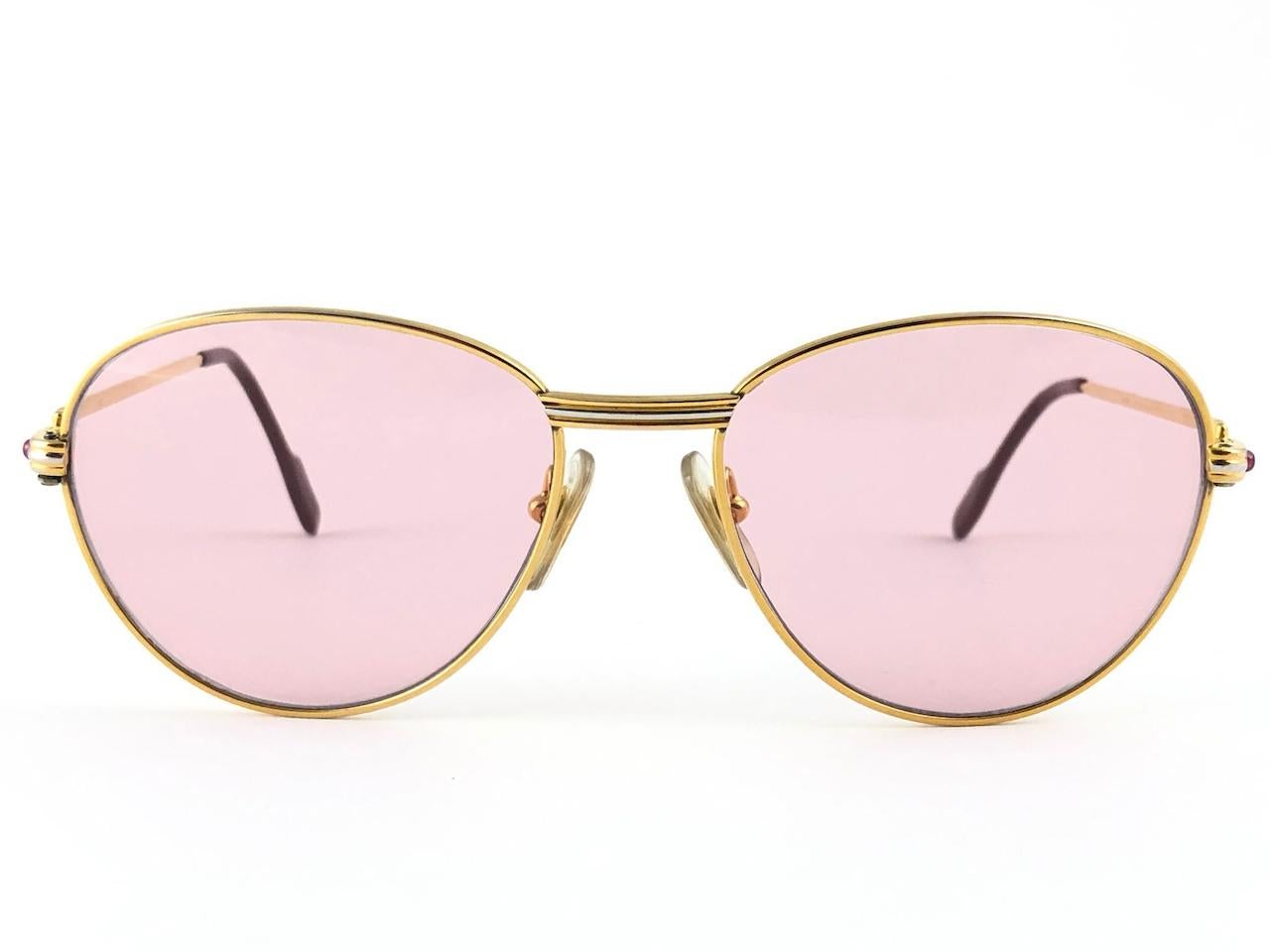 
In Excellent condition Cartier Louis rounded sunglasses with 2 rubies on the side of the frame. Mauve  (uv protection) lenses. Frame is with the famous yellow and white gold accents on the front and on both sides. All hallmarks, from 1989. Red