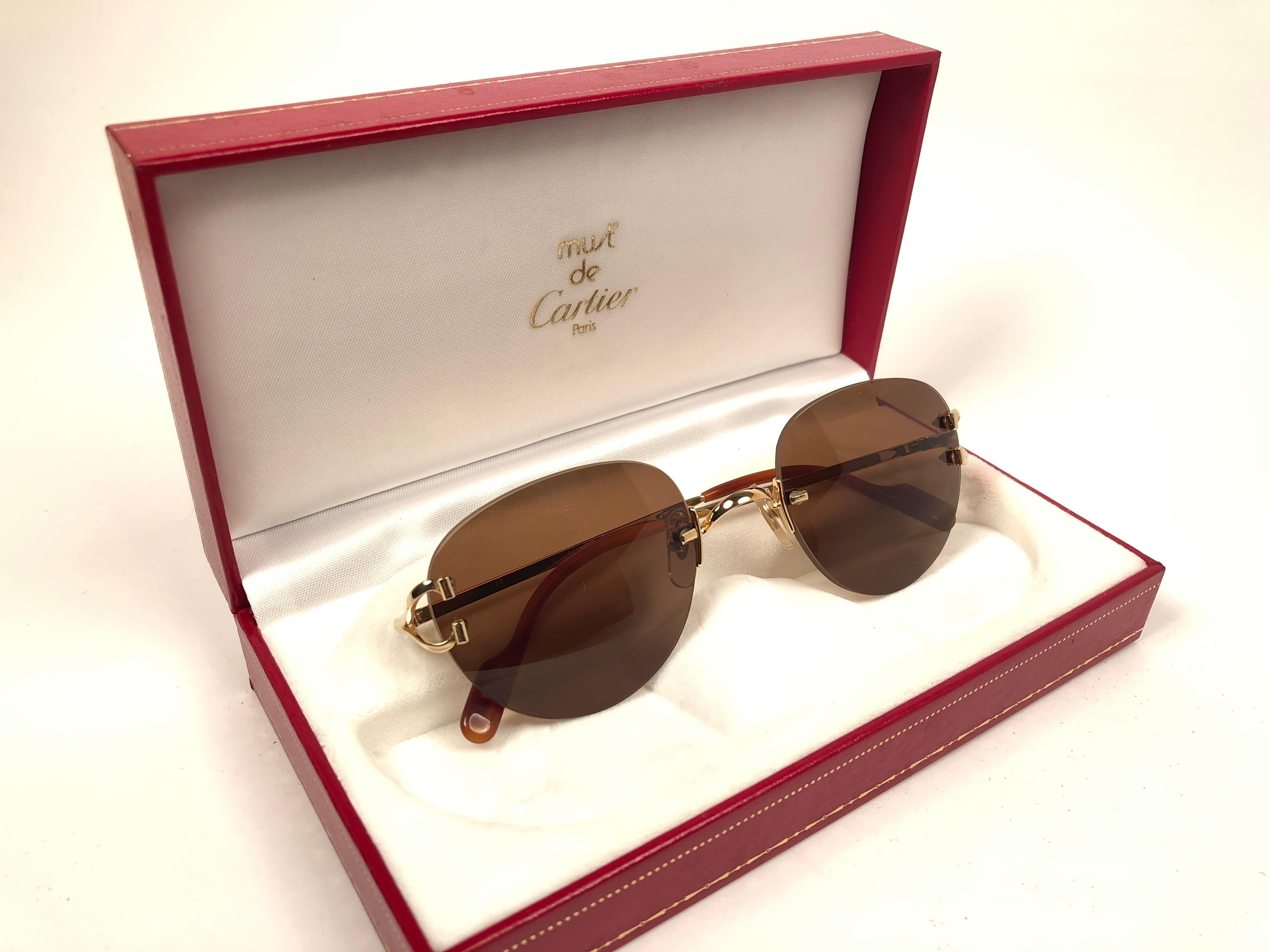 New Cartier Salisbury einzigartige randlose Sonnenbrille mit massiven braunen (UV-Schutz) Gläsern. Rahmen mit goldfarbener Vorder- und Seitenfläche. Alle Markenzeichen. Cartier-Goldzeichen auf den Ohrmuscheln. Sie sind wie ein Paar Juwelen auf der