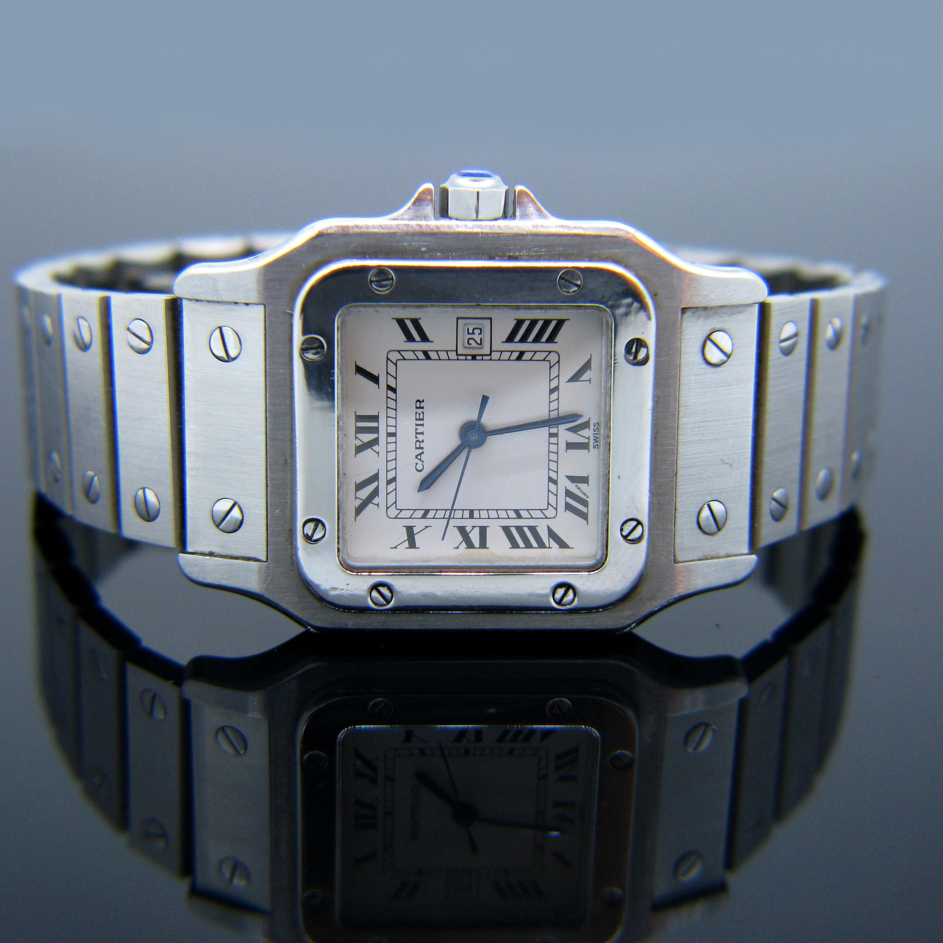 This Cartier watch is from the Santos collection - it is automatic and is made in stainless steel. It is the medium/standard size. The bracelet is made of flat links and the size can be adjusted by removing or adding links. It is in good condition